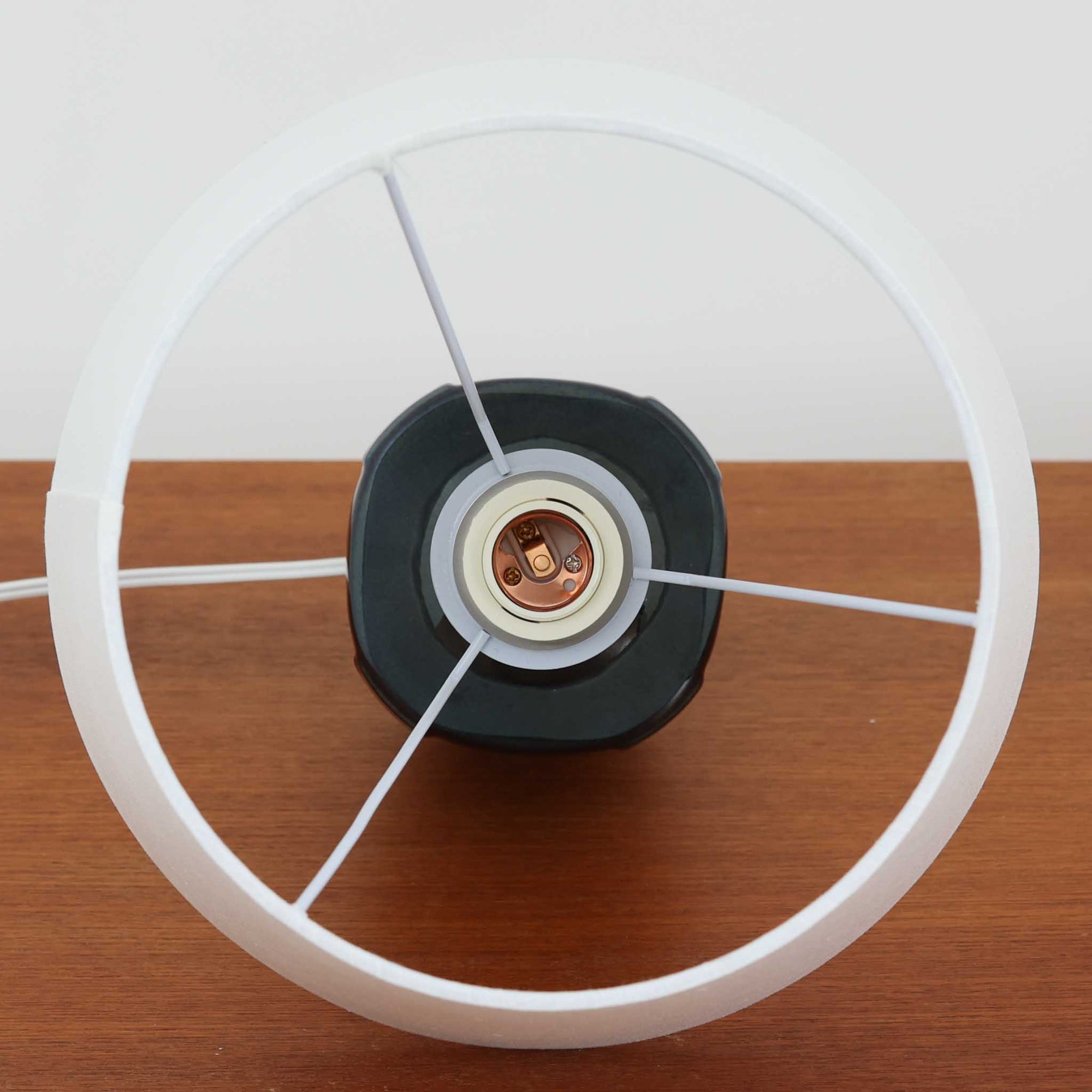 Soholm Keramikのモデル1025、Einar Johansenデザインによるデンマーク製ビンテージテーブルランプです。丸みを持たせた安定感のあるフォルムに、縦方向へ走る繊細なレリーフが美しい陰影を生み、深いネイビーブルーの釉薬が落ち着いた存在感を引き立てています。エイナー・ヨハンセンらしい端正で彫刻的な造形と、スーホルムならではの艶やかな焼き上がりが魅力。リネンシェード越しの柔らかな灯りが陶器の立体感を際立たせ、サイドテーブルやチェスト、ベッドサイドに上質な北欧空間を演出します。経年で深みを増した陶肌の表情と希少モデルならではのコレクション性も楽しめる一台です。