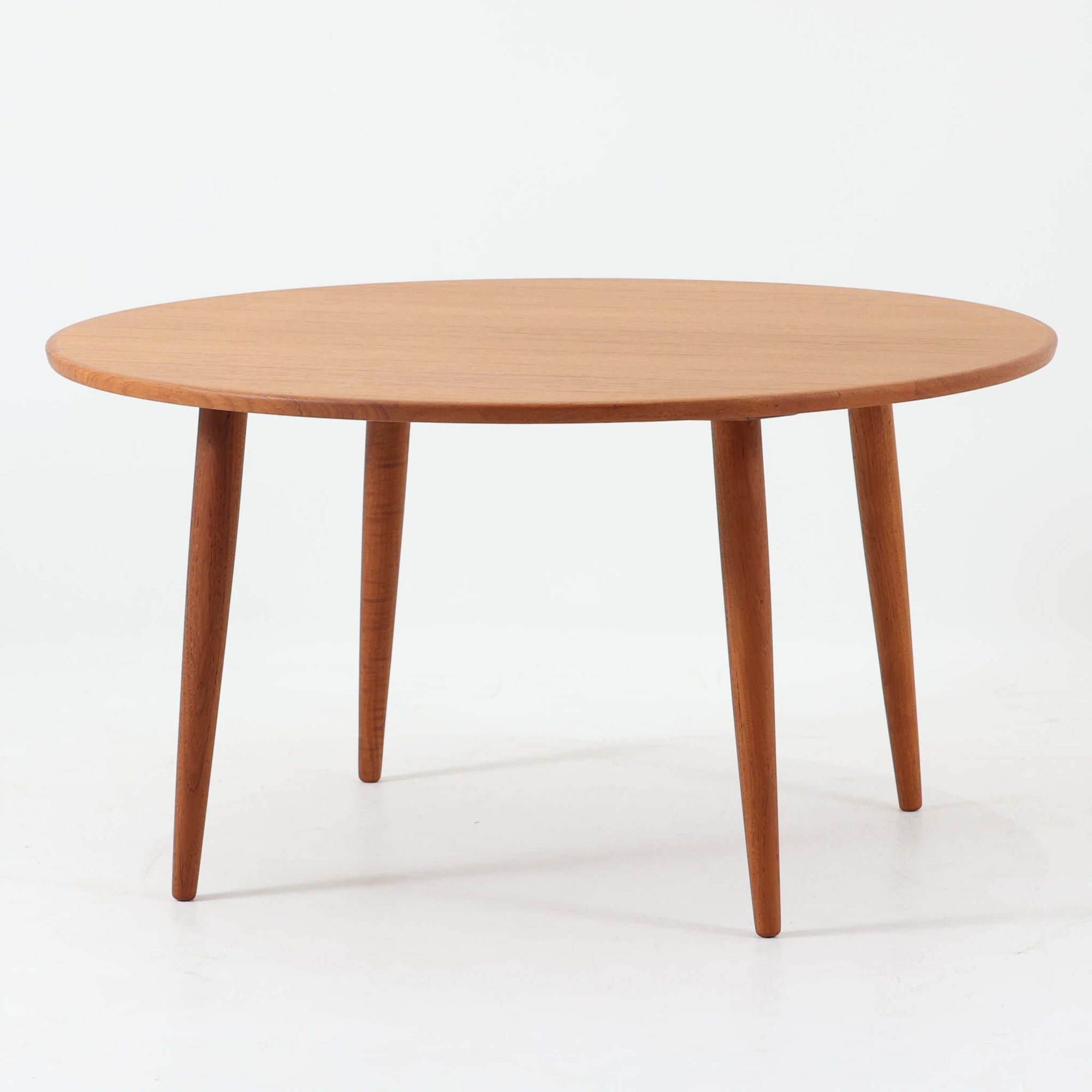 デンマーク製の円形センターテーブルです。チーク材を使用した天板は滑らかな木目と温かみのある色合いが魅力で、シンプルながら上質な存在感を放ちます。すっきりとしたラウンドフォルムと外側へ広がるテーパー脚の構造により、軽やかで安定感のある佇まいを実現。直径98cmの程よいサイズはリビングの中心に置いてくつろぎの空間を演出するほか、来客時のローテーブルとしても活躍します。経年変化による深みのある風合いが北欧ビンテージならではの魅力を引き立てる一台です。