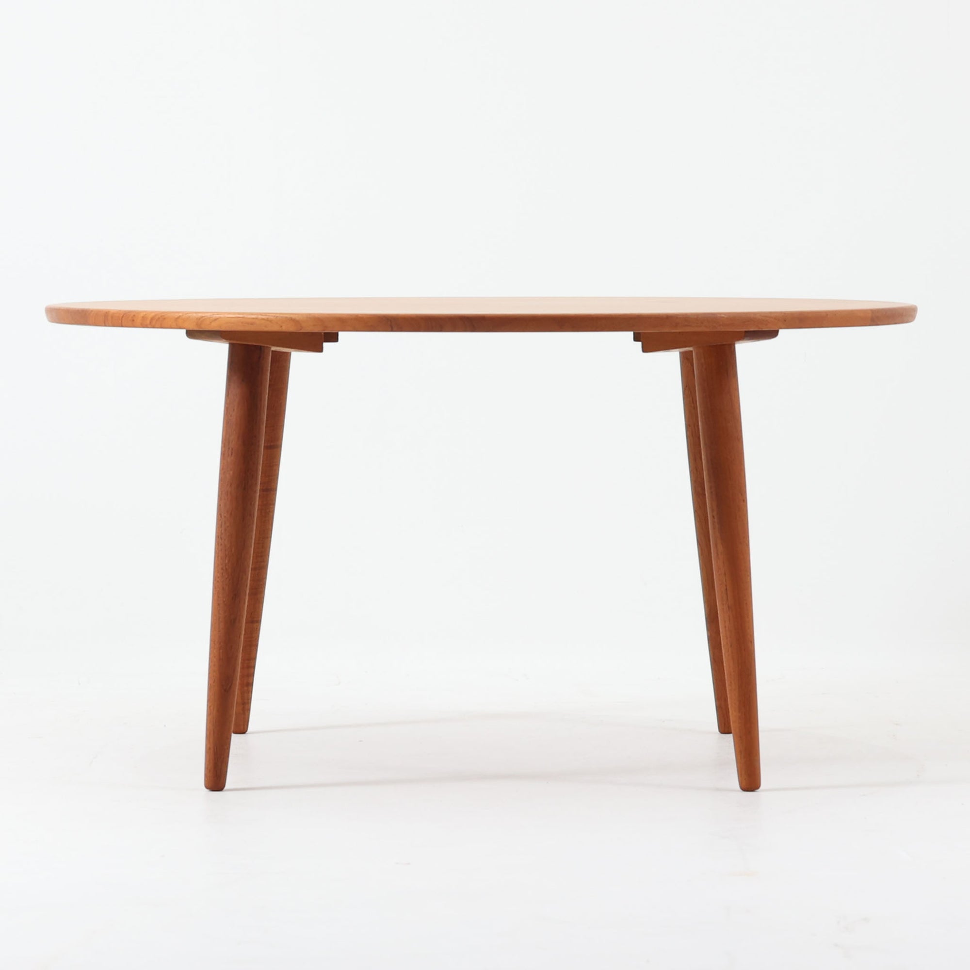 デンマーク製の円形センターテーブルです。チーク材を使用した天板は滑らかな木目と温かみのある色合いが魅力で、シンプルながら上質な存在感を放ちます。すっきりとしたラウンドフォルムと外側へ広がるテーパー脚の構造により、軽やかで安定感のある佇まいを実現。直径98cmの程よいサイズはリビングの中心に置いてくつろぎの空間を演出するほか、来客時のローテーブルとしても活躍します。経年変化による深みのある風合いが北欧ビンテージならではの魅力を引き立てる一台です。