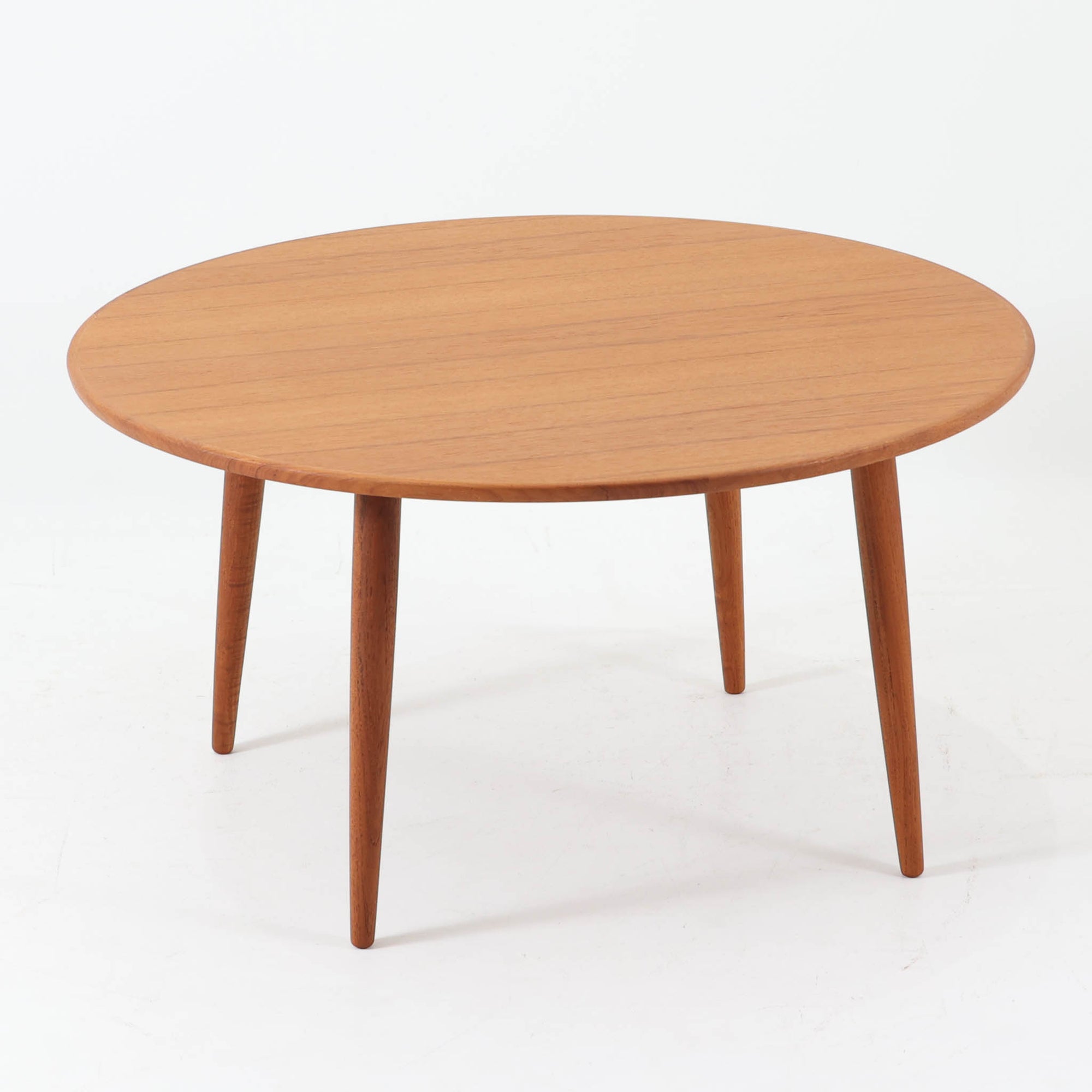 デンマーク製の円形センターテーブルです。チーク材を使用した天板は滑らかな木目と温かみのある色合いが魅力で、シンプルながら上質な存在感を放ちます。すっきりとしたラウンドフォルムと外側へ広がるテーパー脚の構造により、軽やかで安定感のある佇まいを実現。直径98cmの程よいサイズはリビングの中心に置いてくつろぎの空間を演出するほか、来客時のローテーブルとしても活躍します。経年変化による深みのある風合いが北欧ビンテージならではの魅力を引き立てる一台です。