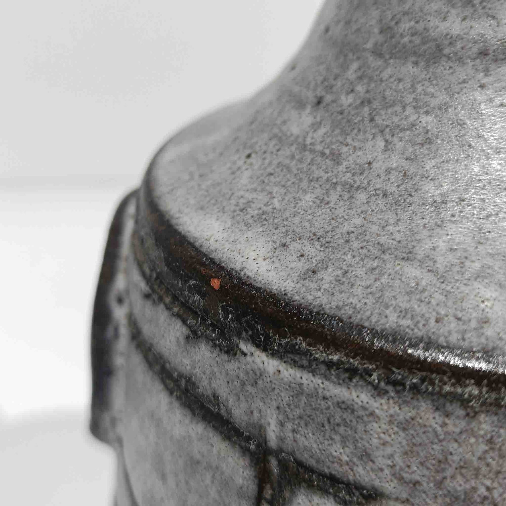 デンマーク製ビンテージテーブルランプです。陶磁器ベースは裾に向かって広がる彫刻的なフォルムを持ち、幾何学的なラインと円形の立体モチーフが規則的に配された、オブジェのような存在感が魅力。マットなグレーを基調とした釉薬に黒の陰影が加わり、手仕事ならではの焼成ムラや表情豊かな質感が際立ちます。リネンシェードから広がるやわらかな灯りが立体意匠を美しく浮かび上がらせ、サイドボードやチェスト、ラウンジ空間のアクセント照明としてもおすすめ。唯一無二の造形美を楽しめる希少なビンテージ品です。