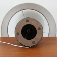 デンマーク製ビンテージテーブルランプです。陶磁器ベースは裾に向かって広がる彫刻的なフォルムを持ち、幾何学的なラインと円形の立体モチーフが規則的に配された、オブジェのような存在感が魅力。マットなグレーを基調とした釉薬に黒の陰影が加わり、手仕事ならではの焼成ムラや表情豊かな質感が際立ちます。リネンシェードから広がるやわらかな灯りが立体意匠を美しく浮かび上がらせ、サイドボードやチェスト、ラウンジ空間のアクセント照明としてもおすすめ。唯一無二の造形美を楽しめる希少なビンテージ品です。