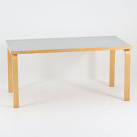 Alvar Aaltoがデザインし、Artekが製作したモデル81Aのダイニングテーブルです。バーチ材の柔らかな木肌とアアルトを象徴するLレッグの曲木構造に、落ち着いたリノリウム天板を組み合わせた、機能美あふれる北欧デザインの名作。幅150cmのゆとりあるサイズは4～6人でのダイニング使用に適しており、ワークスペースやミーティングテーブルとしても活躍します。経年により深みを増した木部の艶やかな風合いと、使い込まれた天板の味わいがビンテージならではの魅力を高め、Artekオリジナルならではの普遍的なデザイン性と希少性が空間に上質な存在感をもたらします。