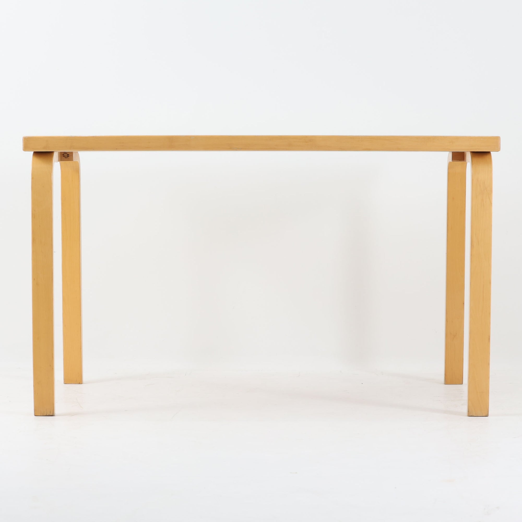 Alvar Aaltoがデザインし、Artek社より製造されたこちらのダイニングテーブルは、落ち着いたグレートーンのリノリウム天板と、美しい木肌を活かしたバーチ材の脚部を組み合わせた、北欧モダンを代表する名作です。L字型に曲げられた脚部は、アアルトらしい柔らかな造形美と高い機能性を兼ね備え、空間に軽やかな印象をもたらします。幅120cmの使い勝手のよいサイズで、ダイニングはもちろんワークスペースにも自然に馴染みます。なお、天板裏面には脚の付け替え跡が確認できたため、安心してお使いいただけるよう現状でしっかり固定しており、脚部の取り外しはできない仕様となっております。