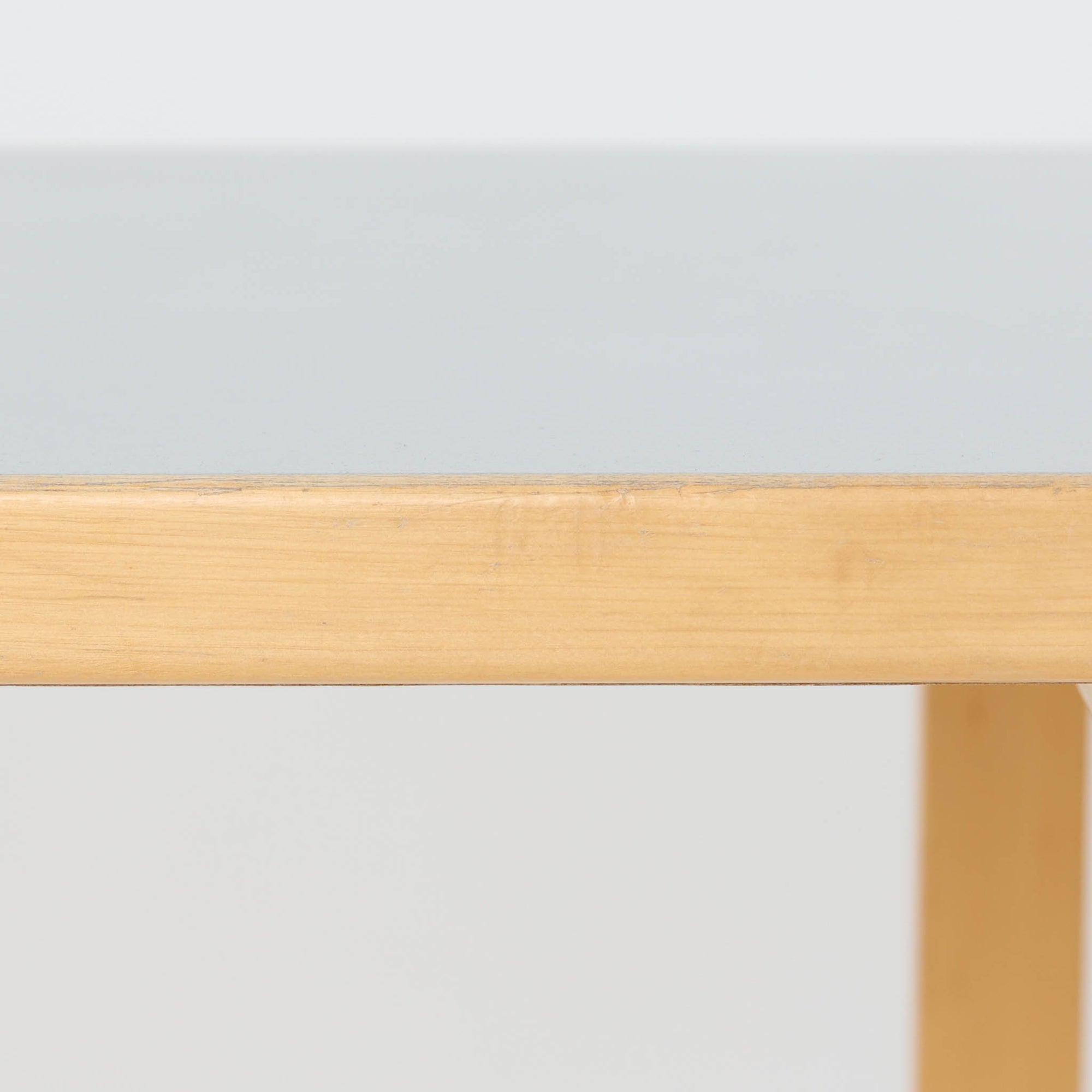 Alvar Aaltoがデザインし、Artek社より製造されたこちらのダイニングテーブルは、落ち着いたグレートーンのリノリウム天板と、美しい木肌を活かしたバーチ材の脚部を組み合わせた、北欧モダンを代表する名作です。L字型に曲げられた脚部は、アアルトらしい柔らかな造形美と高い機能性を兼ね備え、空間に軽やかな印象をもたらします。幅120cmの使い勝手のよいサイズで、ダイニングはもちろんワークスペースにも自然に馴染みます。なお、天板裏面には脚の付け替え跡が確認できたため、安心してお使いいただけるよう現状でしっかり固定しており、脚部の取り外しはできない仕様となっております。