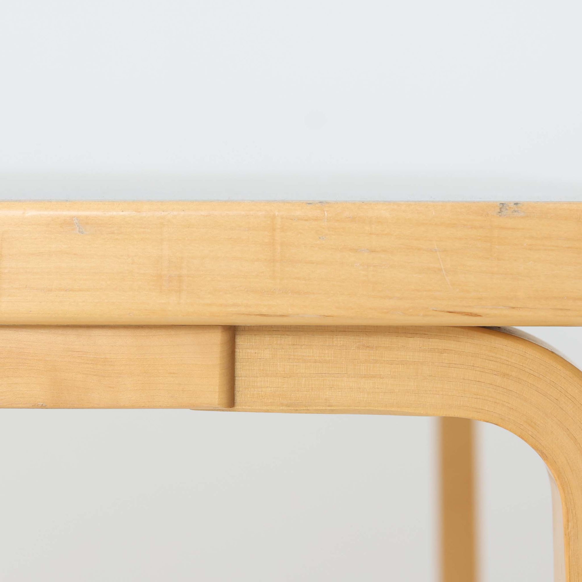 Alvar Aaltoがデザインし、Artek社より製造されたこちらのダイニングテーブルは、落ち着いたグレートーンのリノリウム天板と、美しい木肌を活かしたバーチ材の脚部を組み合わせた、北欧モダンを代表する名作です。L字型に曲げられた脚部は、アアルトらしい柔らかな造形美と高い機能性を兼ね備え、空間に軽やかな印象をもたらします。幅120cmの使い勝手のよいサイズで、ダイニングはもちろんワークスペースにも自然に馴染みます。なお、天板裏面には脚の付け替え跡が確認できたため、安心してお使いいただけるよう現状でしっかり固定しており、脚部の取り外しはできない仕様となっております。