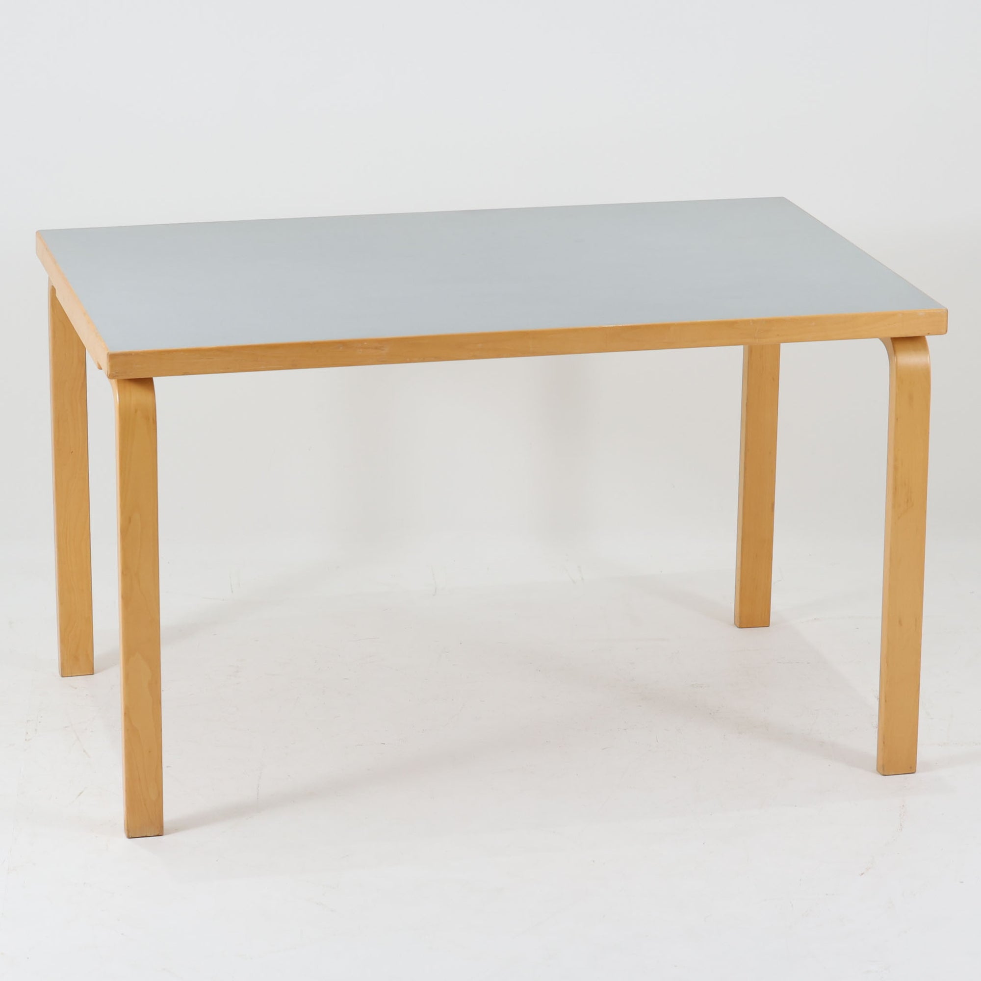 Alvar Aaltoがデザインし、Artekが製作したモデル81Bのダイニングテーブルです。バーチ材の柔らかな木肌と、アアルトを象徴するLレッグの曲木構造にリノリウム天板を組み合わせた、北欧モダンを代表するタイムレスな一台。幅120cmの使いやすいサイズは4人掛けのダイニングテーブルとしてはもちろん、書斎やワークスペースのデスクとしても取り入れやすい設計です。経年によって深みを増した木部の艶やかな表情と、使い込まれた天板の落ち着いた風合いがビンテージならではの魅力を高め、Artekオリジナルの希少性と普遍的なデザイン美が空間に上質な存在感をもたらします。