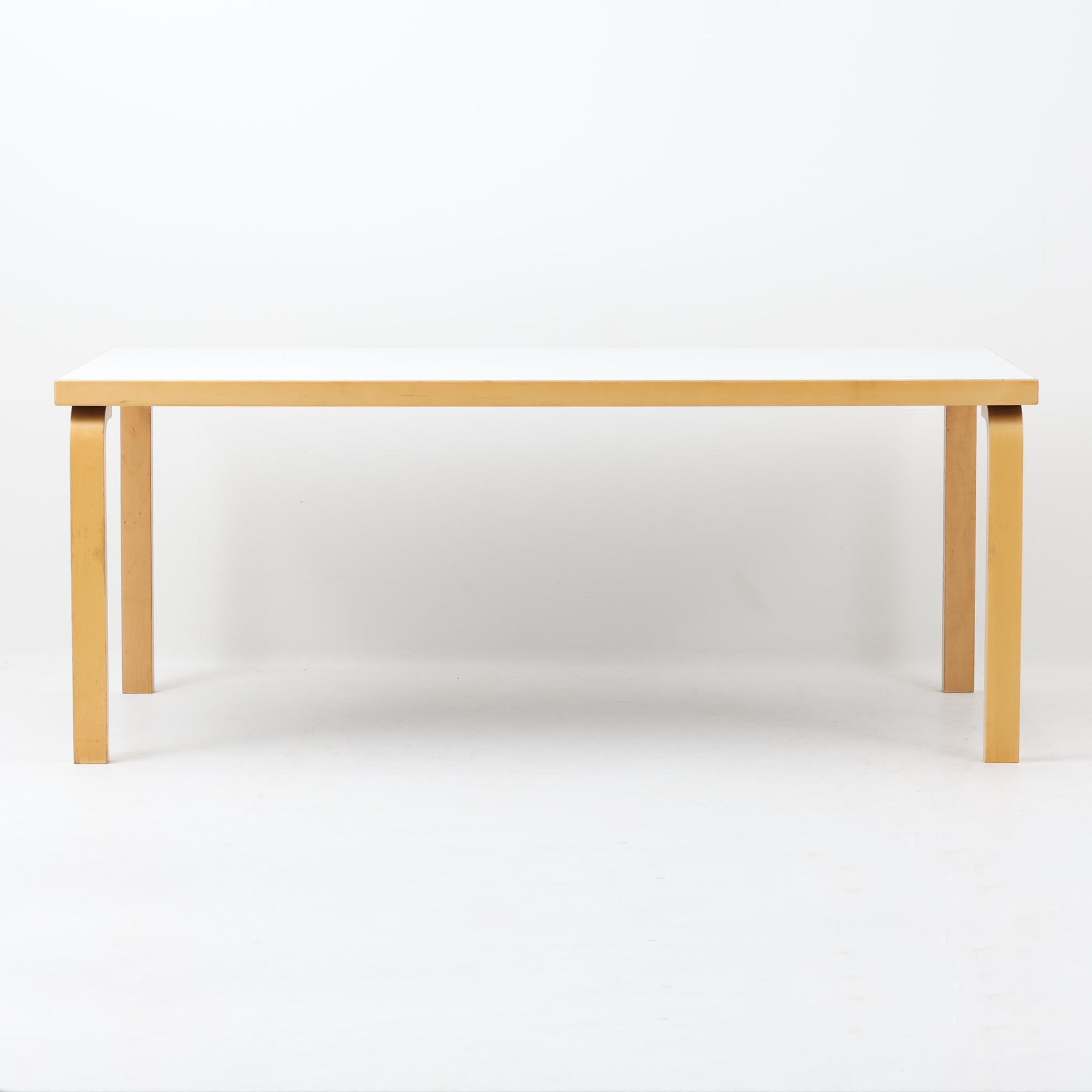 Alvar Aaltoが手掛け、Artekより製造された北欧デザインを代表するダイニングテーブルです。天板には実用性に優れたリノリウム、フレームにはバーチ材を使用し、アアルトならではの美しいLレッグ構造が軽やかな印象を与えます。無駄を削ぎ落としたシンプルなフォルムは空間に自然に溶け込み、幅182cmのゆとりあるサイズでダイニングやワークスペースにも最適です。機能美と耐久性を兼ね備えた名作として長く愛され続けており、経年による風合いも楽しめる北欧ビンテージならではの魅力を備えています。