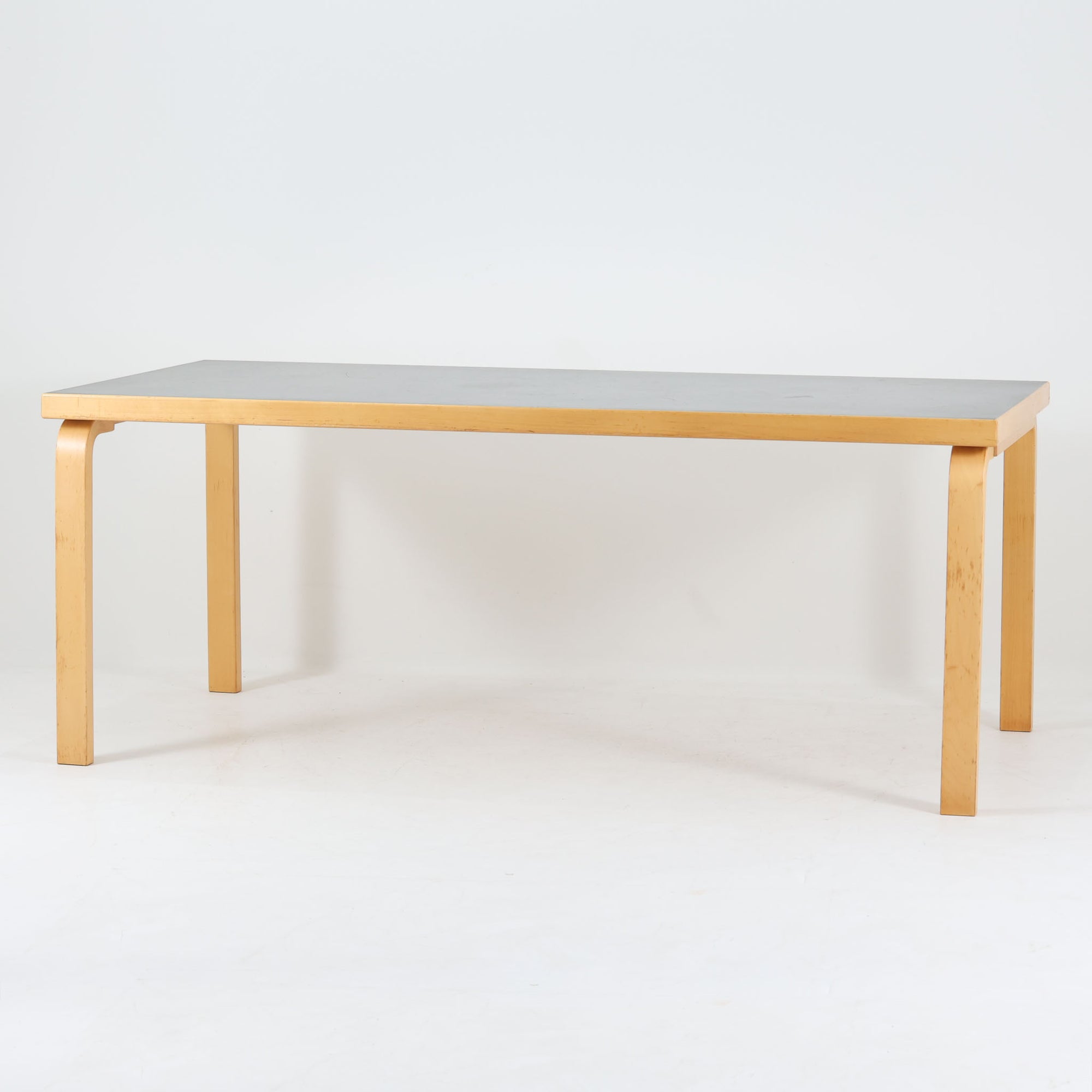 Alvar Aaltoが手掛けたArtekの名作「Table 83」です。バーチ材のフレームにリノリウム天板を組み合わせた、機能美あふれるデザインが魅力。アアルトを象徴するLレッグ構造は、無駄を削ぎ落とした軽やかなフォルムと優れた耐久性を両立しています。幅182cmのゆとりあるサイズはダイニングテーブルとしてはもちろん、ワークテーブルやミーティングテーブルとしても活躍。長年愛され続ける北欧モダンデザインとビンテージならではの風合いを楽しめる一台です。