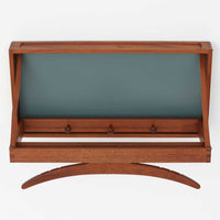 Adam Hoff & Poul Ostergaardがデザインし、Virum Mobelsnickeriにより製作された「The Hanger」ハンガーラックです。チーク材の温かみある木目と、優雅な曲線を描くベースのフォルムが印象的なデザイン。内部にはフックが備えられ、コートや帽子などを掛けて収納できます。フロントのフラップを開くとハンガー部分が現れる機能的な構造で、使用しないときはすっきりとした壁面収納として美しく収まります。革ベルトによる固定や細部の造りにも職人技が感じられる、北欧ビンテージならではの洗練された一品です。