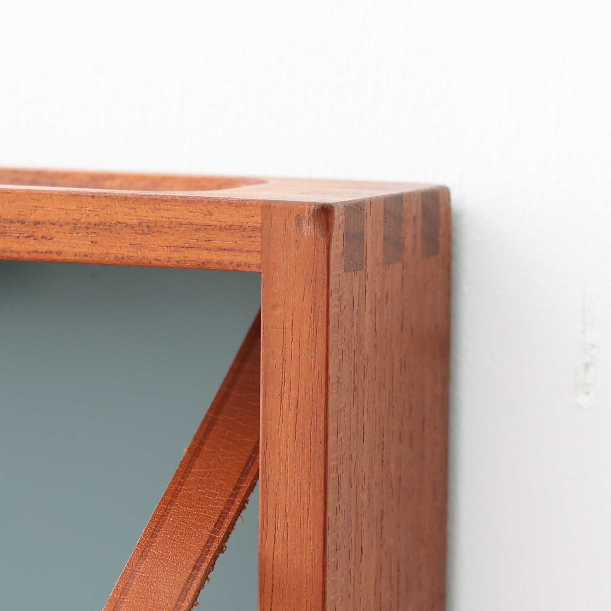 Adam Hoff &amp; Poul Ostergaardがデザインし、Virum Mobelsnickeriにより製作された「The Hanger」ハンガーラックです。チーク材の温かみある木目と、優雅な曲線を描くベースのフォルムが印象的なデザイン。内部にはフックが備えられ、コートや帽子などを掛けて収納できます。フロントのフラップを開くとハンガー部分が現れる機能的な構造で、使用しないときはすっきりとした壁面収納として美しく収まります。革ベルトによる固定や細部の造りにも職人技が感じられる、北欧ビンテージならではの洗練された一品です。