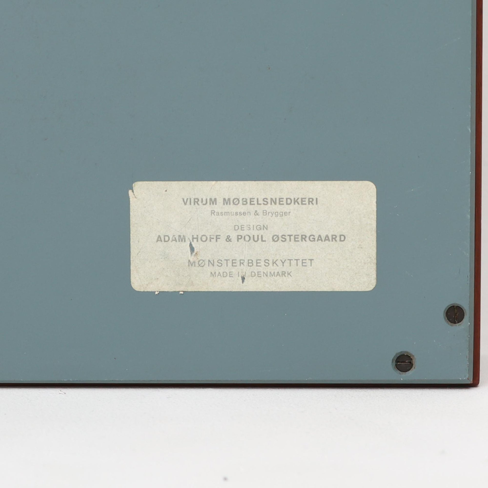 Adam Hoff &amp; Poul Ostergaardがデザインし、Virum Mobelsnickeriにより製作された「The Hanger」ハンガーラックです。チーク材の温かみある木目と、優雅な曲線を描くベースのフォルムが印象的なデザイン。内部にはフックが備えられ、コートや帽子などを掛けて収納できます。フロントのフラップを開くとハンガー部分が現れる機能的な構造で、使用しないときはすっきりとした壁面収納として美しく収まります。革ベルトによる固定や細部の造りにも職人技が感じられる、北欧ビンテージならではの洗練された一品です。