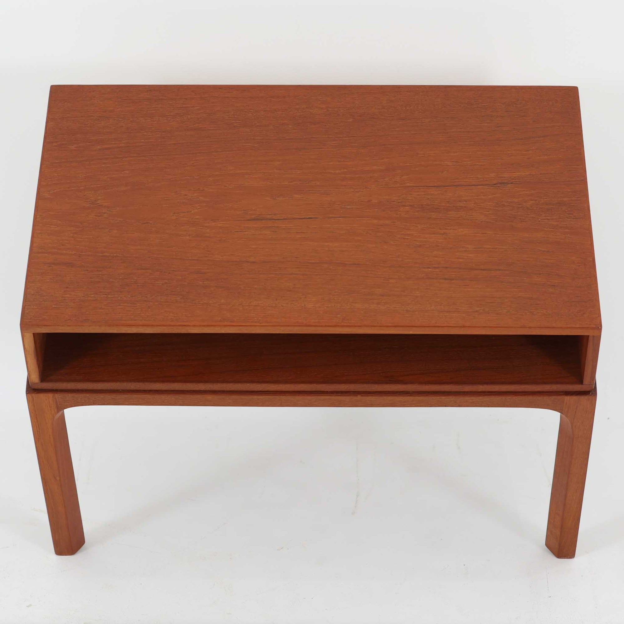Kai Kristiansenがデザインし、Aksel Kjersgaardが手掛けたNo.383 サイドテーブルです。チーク材の美しい木目と経年により深みを増した色合いが魅力で、天板下に設けられたオープンスペースが軽やかな印象と実用性を兼ね備えています。脚部は内側に滑らかな曲線で接合されており、シンプルながらも洗練された構造美が際立つ一台。ソファサイドやベッドサイドでの使用はもちろん、雑誌や小物をすっきりと収める収納としても活躍します。北欧ビンテージならではの丁寧な木工技術と希少性を感じられる逸品です。