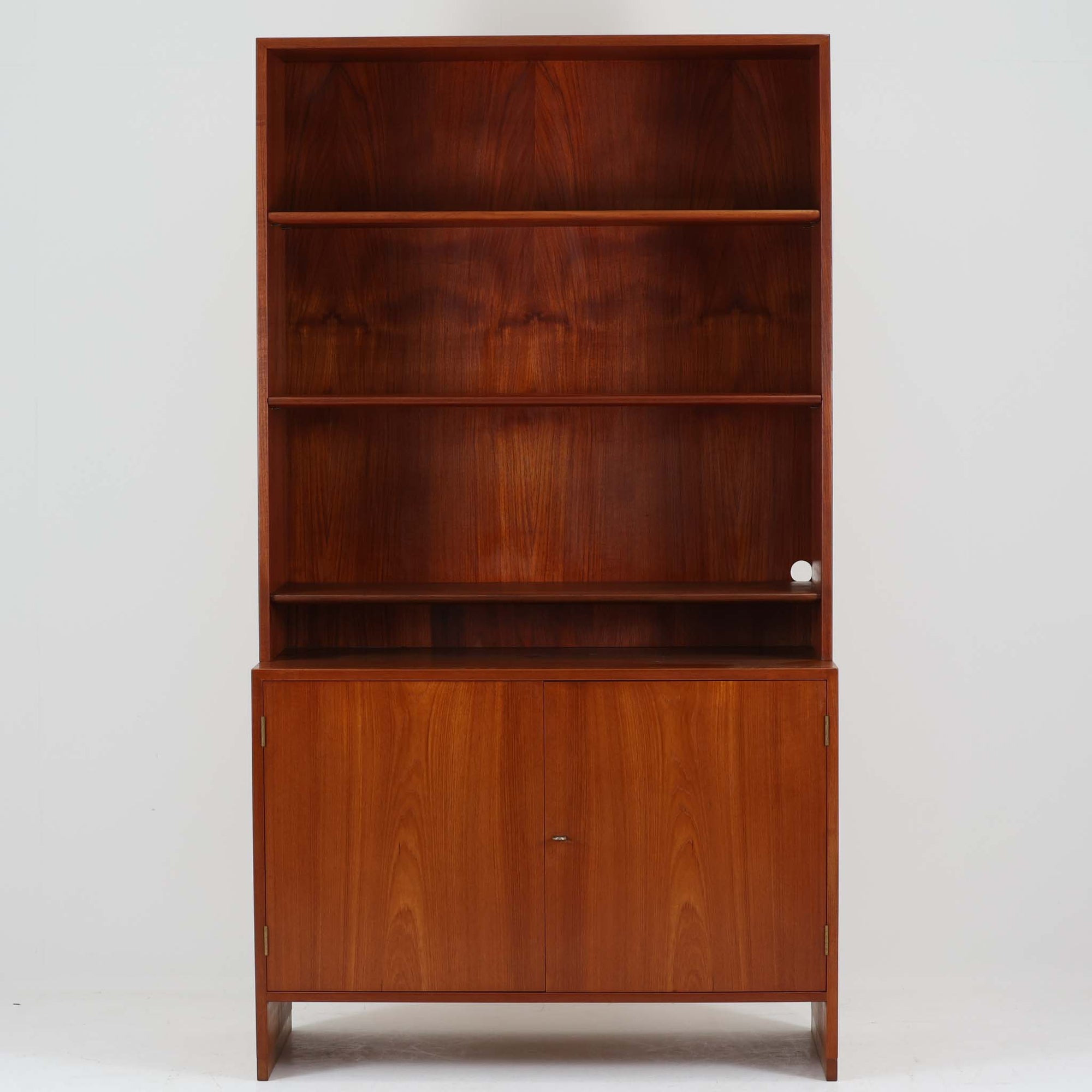 Hans J. Wegnerがデザインし、Ry Moblerが製作したディスプレイシェルフです。美しい木目をもつチーク材を主体に、内部や構造部にはオーク材、金具には真鍮を組み合わせた上質なつくりが魅力。上部のオープン棚は飾り棚として器やオブジェ、本を美しく見せ、下部の開き戸収納は細かい日用品や書類をすっきり隠して収納できます。直線的で端正なフォルムの中に、ウェグナーらしい丁寧な木工技術と素材の美しさが息づき、経年で深みを増した色艶が空間に格別の存在感を添える一品です。リビングや書斎、ショップ什器としてもおすすめです。