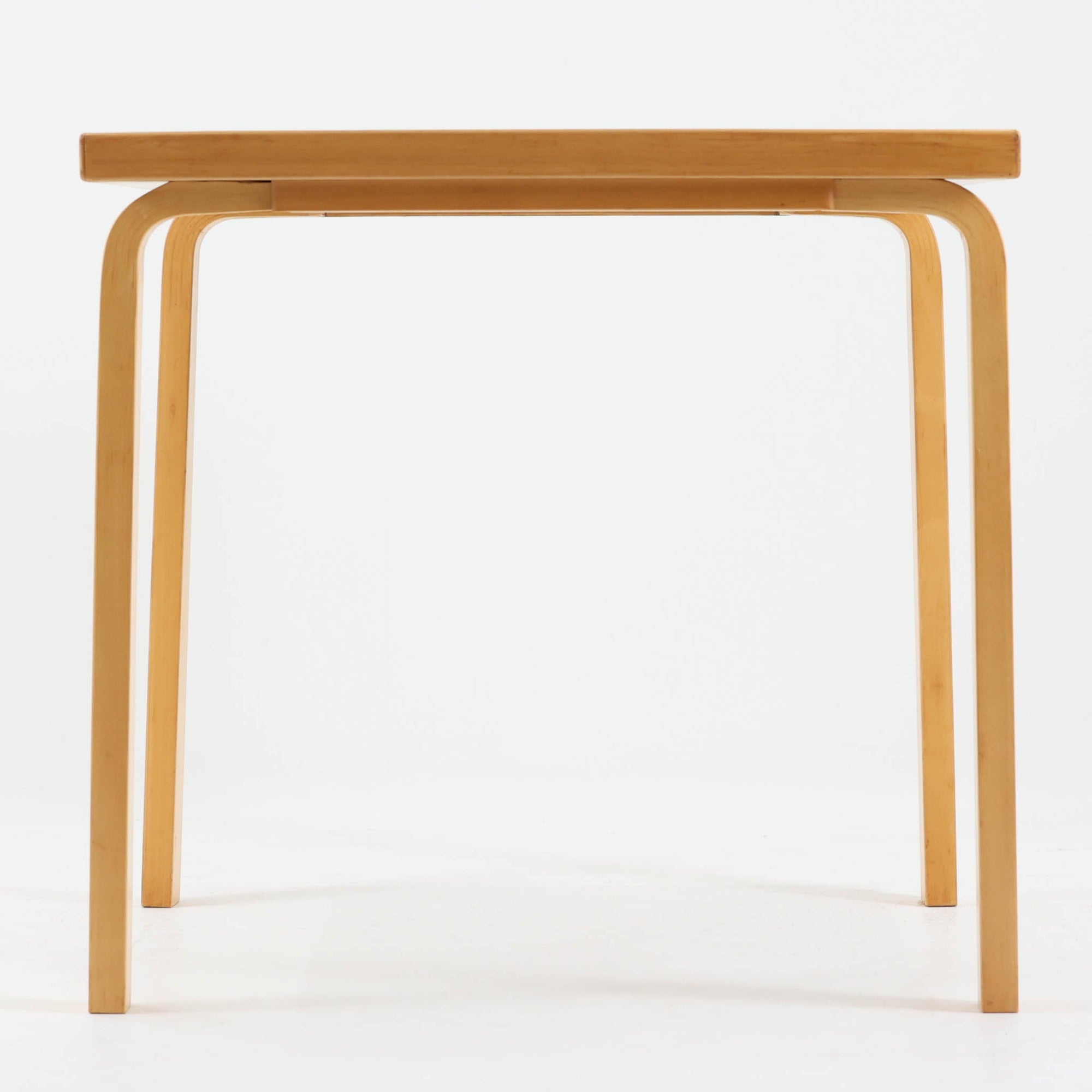 Alvar Aaltoがデザインし、Artekより製作された「81C」ダイニングテーブルです。バーチ材を用いたフレームに、天板には落ち着いた質感のリノリウムを組み合わせたシンプルで機能的なデザインが特徴。脚部にはアアルトを象徴するL字型の曲木構造が採用されており、軽やかで柔らかな印象を与えます。幅75cmの正方形サイズはダイニングはもちろんワークテーブルとしても使いやすく、日常の空間に北欧デザインの美しさと実用性をもたらすビンテージ家具です。本個体は、脚部の5枚レイヤー構造、1973年以降に採用されたプラスネジ、および天板裏の3段構成スタンプの仕様から、1973年～1990年代始めに掛けて製造されたと思われます。