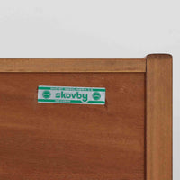 Skovby Mobelfabrik（スコービー）が手掛けた、幅195cmの存在感あるサイドボードです。チーク材の豊かな木目を生かした端正な佇まいに、横方向へ連続する扉と控えめな掘り込み取っ手がすっきりとした印象を与えます。内部には収納スペースに加えてトレー状の引き出しを備え、食器やカトラリーなどの整理にも便利な構成。ダイニング収納としてはもちろん、リビングでオーディオやアートを飾るローボードとしても活躍します。長い年月を経たチーク材ならではの深みある色艶も魅力の北欧ビンテージ品です。