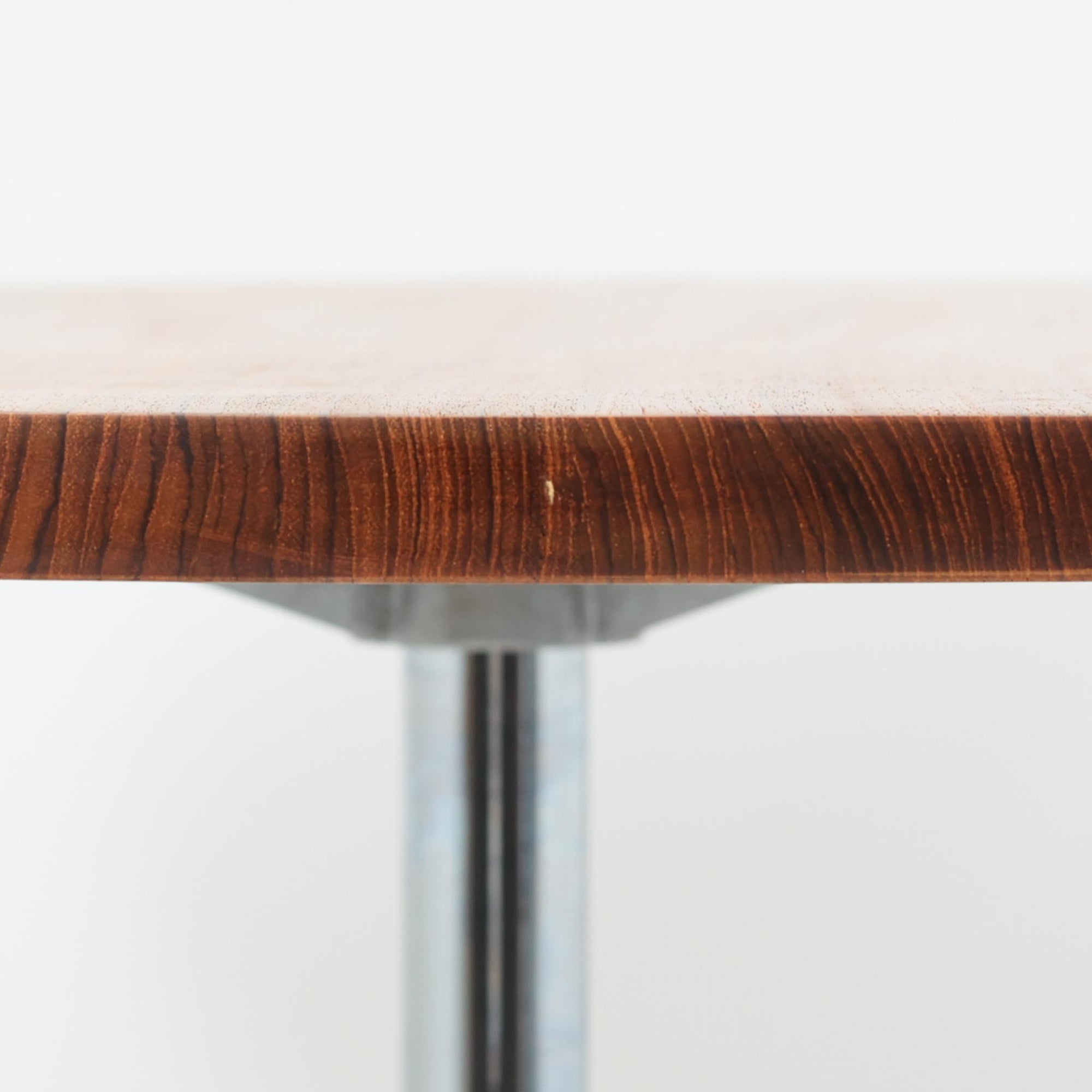Arne Jacobsenがデザインし、Fritz Hansenが製作した円形ダイニングテーブルです。直径90cmのチーク無垢天板は、豊かな木目と滑らかな円形フォルムが美しく、空間に柔らかな印象をもたらします。シャープなスチール製の一本脚と4本スポークベースが軽快で洗練された佇まいを生み、ヤコブセンらしい機能美が際立つ一台。2～4人で使いやすいサイズ感で、ダイニングテーブルとしてはもちろん、カフェテーブルやラウンジ空間での打ち合わせ用テーブルとしてもおすすめです。中でもチーク無垢材仕様の個体は流通数が少なく珍しく、北欧ビンテージ市場でも希少性の高いモデルとして魅力を放ちます。経年により深みを増した木肌と無駄のない構造が、空間に上質な存在感を添えてくれます。
