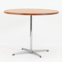 Arne Jacobsenがデザインし、Fritz Hansenが製作した円形ダイニングテーブルです。直径90cmのチーク無垢天板は、豊かな木目と滑らかな円形フォルムが美しく、空間に柔らかな印象をもたらします。シャープなスチール製の一本脚と4本スポークベースが軽快で洗練された佇まいを生み、ヤコブセンらしい機能美が際立つ一台。2～4人で使いやすいサイズ感で、ダイニングテーブルとしてはもちろん、カフェテーブルやラウンジ空間での打ち合わせ用テーブルとしてもおすすめです。中でもチーク無垢材仕様の個体は流通数が少なく珍しく、北欧ビンテージ市場でも希少性の高いモデルとして魅力を放ちます。経年により深みを増した木肌と無駄のない構造が、空間に上質な存在感を添えてくれます。