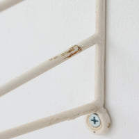 Nils Strinningがデザインし、String Design ABが製造したチーク材のウォールシェルフです。細身の金属製サイドフレームに3枚の木製棚板を組み合わせた軽快な構成で、圧迫感を抑えながら書籍や器、オブジェなどを美しく飾ることができます。棚板の位置を調整しやすい機能的な構造と、直線的で無駄のない造形は北欧らしい合理性を感じさせ、チーク材の経年による深い色合いと金属フレームの対比も魅力。リビングや書斎、店舗空間の壁面を有効に使える存在感ある一台です。