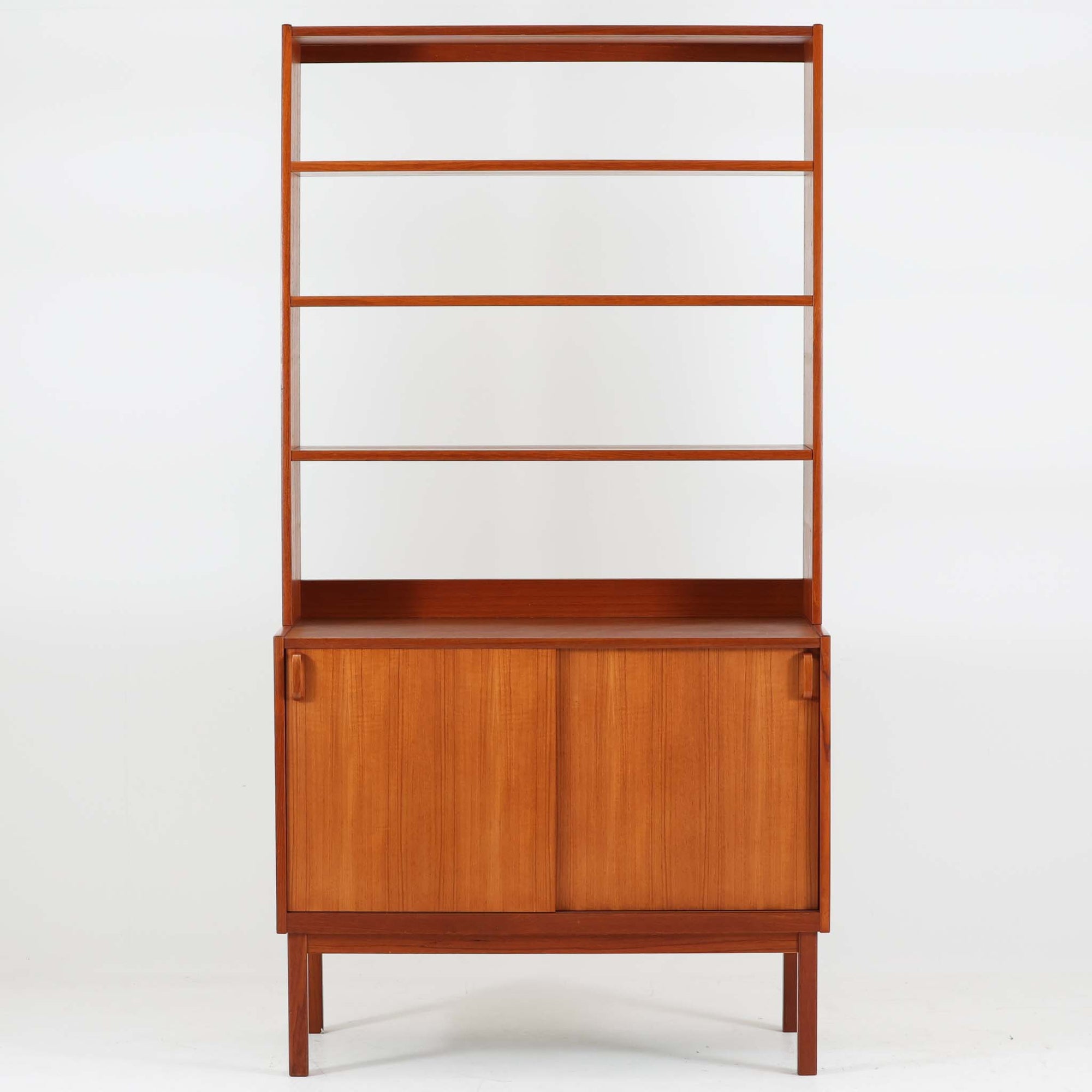 B. Fridhagenがデザインし、Bodaforsが製作したディスプレイシェルフです。チーク材ならではの美しい木目と経年で深みを増した艶やかな色合いが魅力で、上部のオープン棚と下部の引き戸収納を組み合わせた実用性の高い構成が北欧らしい機能美を感じさせます。幅90cmのすっきりとしたサイズは、書籍やオブジェ、器のディスプレイはもちろん、リビングや書斎での見せる収納と隠す収納を両立。細身の脚部が軽やかな印象を添え、Bodaforsらしい丁寧な木工技術とビンテージならではの希少性が空間に上質な存在感をもたらします。