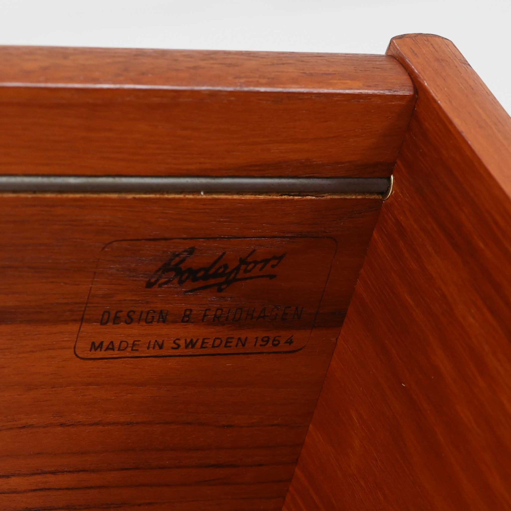 B. Fridhagenがデザインし、Bodaforsが製作したディスプレイシェルフです。チーク材ならではの美しい木目と経年で深みを増した艶やかな色合いが魅力で、上部のオープン棚と下部の引き戸収納を組み合わせた実用性の高い構成が北欧らしい機能美を感じさせます。幅90cmのすっきりとしたサイズは、書籍やオブジェ、器のディスプレイはもちろん、リビングや書斎での見せる収納と隠す収納を両立。細身の脚部が軽やかな印象を添え、Bodaforsらしい丁寧な木工技術とビンテージならではの希少性が空間に上質な存在感をもたらします。