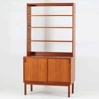 B. Fridhagenがデザインし、Bodaforsが製作したディスプレイシェルフです。チーク材ならではの美しい木目と経年で深みを増した艶やかな色合いが魅力で、上部のオープン棚と下部の引き戸収納を組み合わせた実用性の高い構成が北欧らしい機能美を感じさせます。幅90cmのすっきりとしたサイズは、書籍やオブジェ、器のディスプレイはもちろん、リビングや書斎での見せる収納と隠す収納を両立。細身の脚部が軽やかな印象を添え、Bodaforsらしい丁寧な木工技術とビンテージならではの希少性が空間に上質な存在感をもたらします。