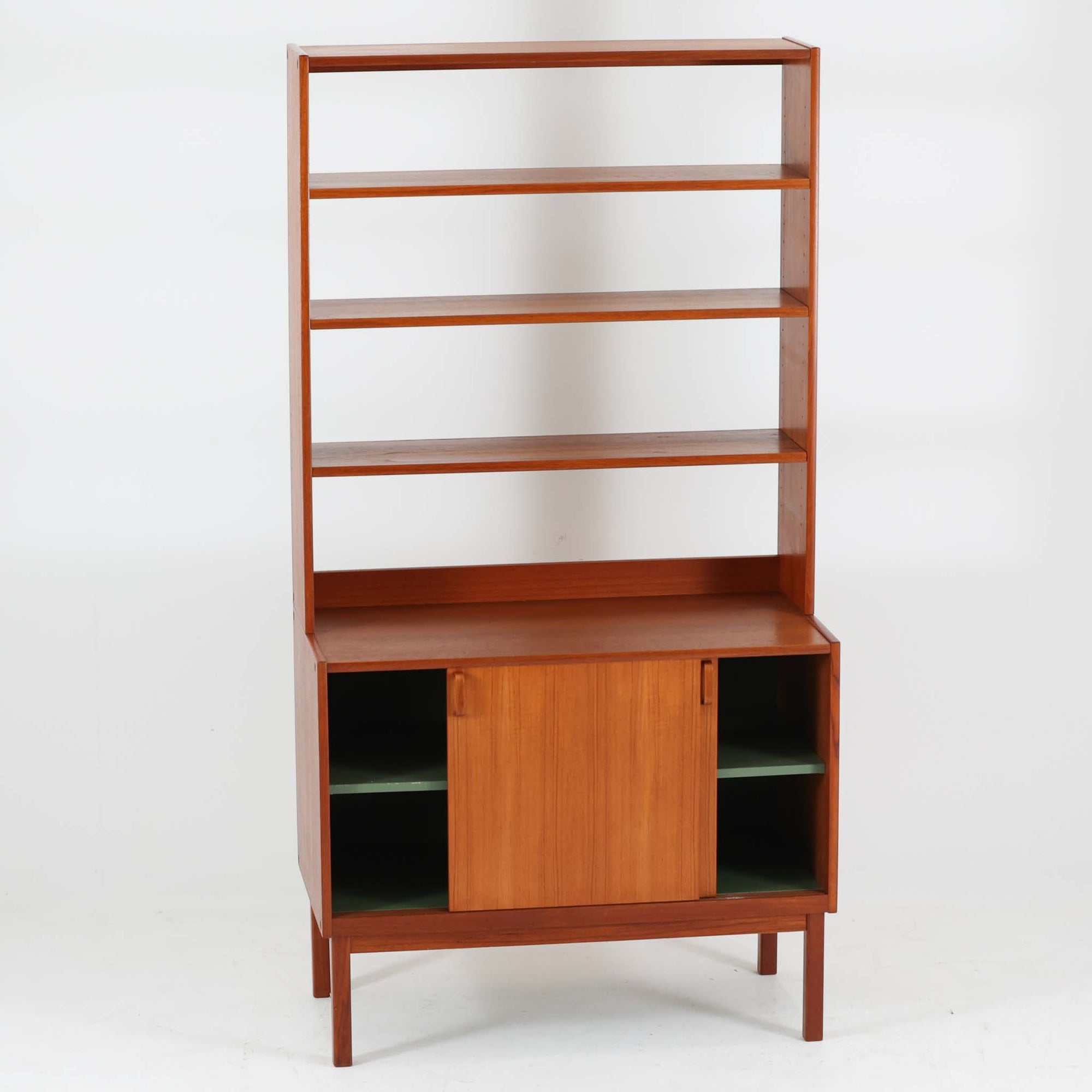 B. Fridhagenがデザインし、Bodaforsが製作したディスプレイシェルフです。チーク材ならではの美しい木目と経年で深みを増した艶やかな色合いが魅力で、上部のオープン棚と下部の引き戸収納を組み合わせた実用性の高い構成が北欧らしい機能美を感じさせます。幅90cmのすっきりとしたサイズは、書籍やオブジェ、器のディスプレイはもちろん、リビングや書斎での見せる収納と隠す収納を両立。細身の脚部が軽やかな印象を添え、Bodaforsらしい丁寧な木工技術とビンテージならではの希少性が空間に上質な存在感をもたらします。