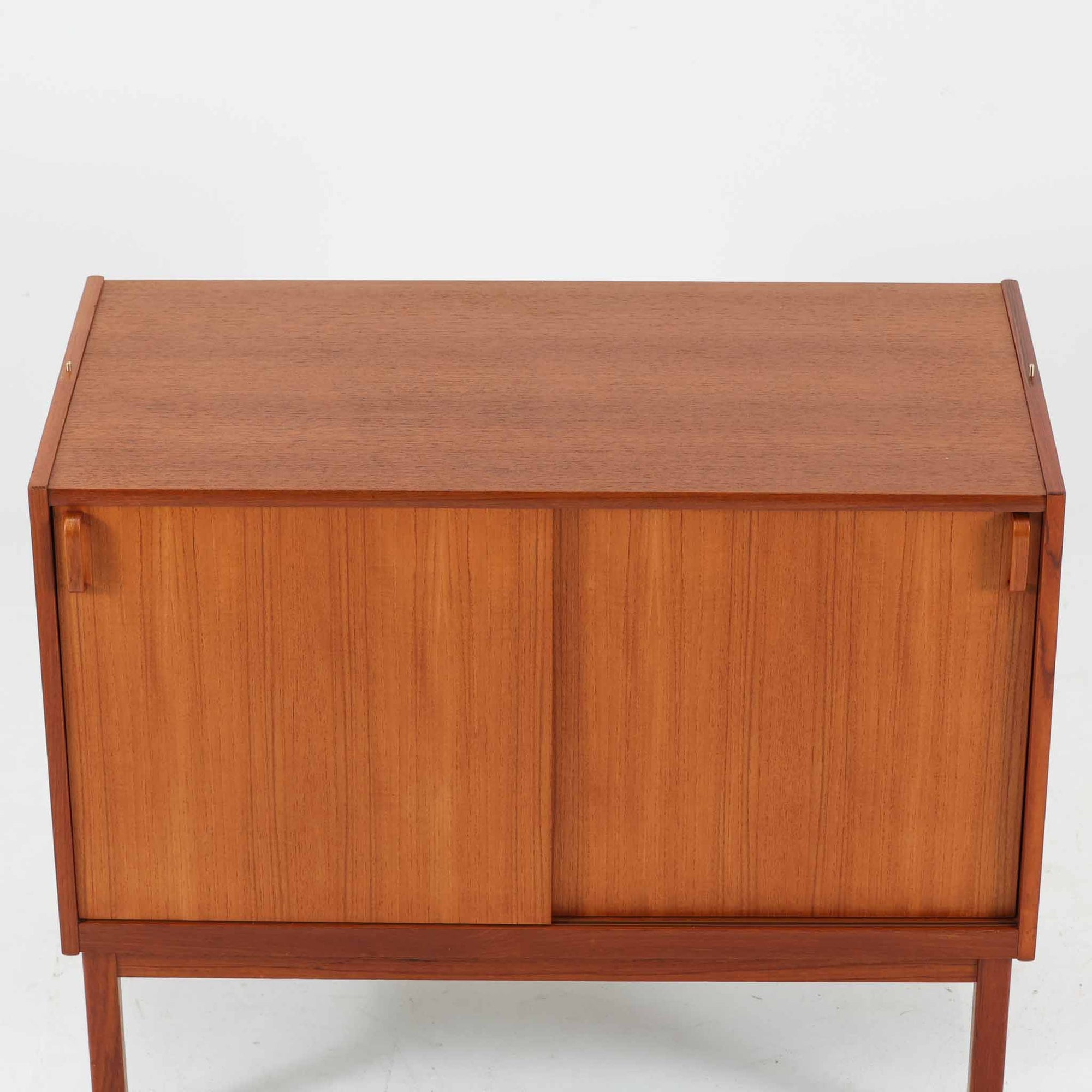 B. Fridhagenがデザインし、Bodaforsが製作したディスプレイシェルフです。チーク材ならではの美しい木目と経年で深みを増した艶やかな色合いが魅力で、上部のオープン棚と下部の引き戸収納を組み合わせた実用性の高い構成が北欧らしい機能美を感じさせます。幅90cmのすっきりとしたサイズは、書籍やオブジェ、器のディスプレイはもちろん、リビングや書斎での見せる収納と隠す収納を両立。細身の脚部が軽やかな印象を添え、Bodaforsらしい丁寧な木工技術とビンテージならではの希少性が空間に上質な存在感をもたらします。