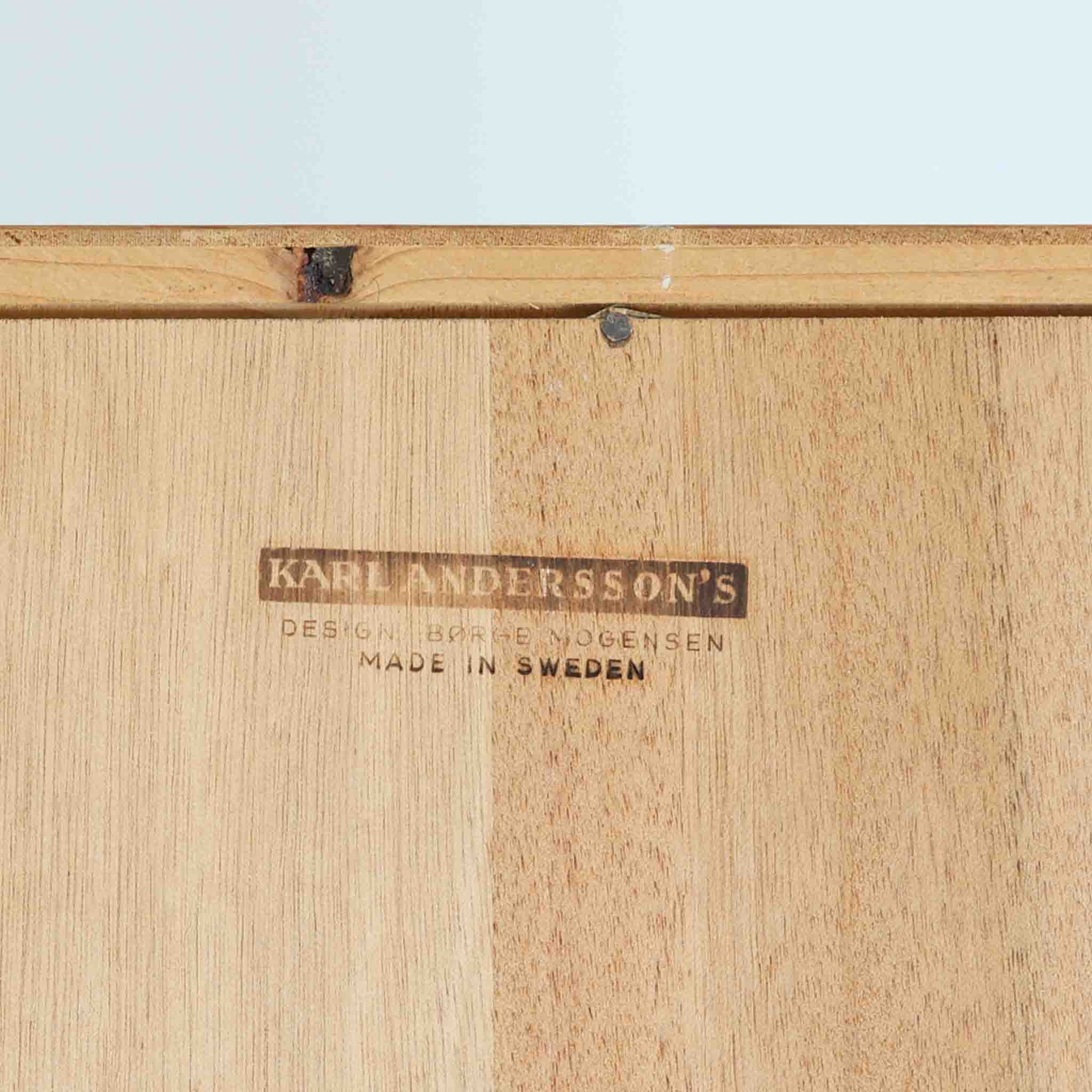 Borge Mogensenがデザインを手掛け、Karl Andersson &amp; Sonerが製造したスリムシェルフです。オーク材の美しい木目を生かした端正なデザインに、オープンシェルフと4杯の引出しを組み合わせることで、飾る収納と隠す収納を一台で実現しています。無駄を削ぎ落とした直線的なフォルムは、モーエンセンらしい機能美が感じられる佇まい。書籍やオブジェ、食器などを美しくディスプレイしながら整理でき、経年によって深みを増した木肌と丁寧な造りが北欧ビンテージならではの魅力を引き立てます。