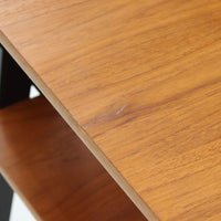 チーク材の天板とビーチ材の棚板、メタル支柱を組み合わせた異素材ミックスの構造が印象的で、ブラック塗装のフレームが全体を引き締めた軽快なデザインに仕上がっています。引き出し付きで小物収納に便利なほか、雑誌やレコードを立て掛けられる機能的な仕切りも備え、リビングや玄関先など多用途に活躍。北欧ビンテージらしい実用性と個性を兼ね備えた一台です。