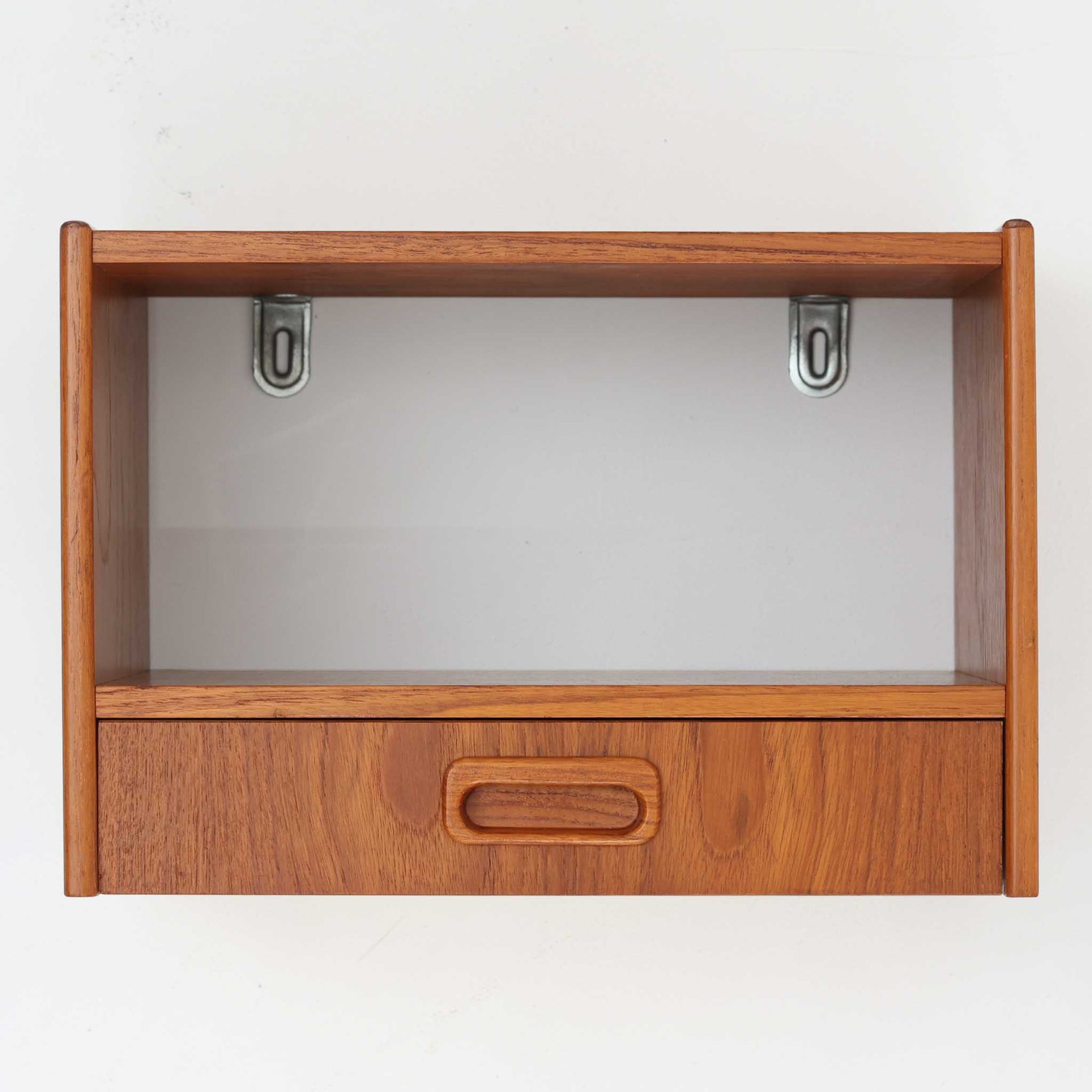 スウェーデン製チーク材ウォールシェルフです。壁面にすっきりと収まるコンパクトなサイズに、オープン棚と引き出しを組み合わせた実用性の高いデザインが魅力。丸みを帯びた側板や掘り込み式の引き手が北欧らしい柔らかな印象を添え、チーク材の美しい木目と経年で深みを増した艶が上質な存在感を演出します。お気に入りのオブジェや本、時計を飾るディスプレイスペースとしてはもちろん、玄関やベッドサイドで小物収納としても活躍。限られた空間を有効活用しながら、ビンテージならではの温もりと希少性を楽しめる一台です。