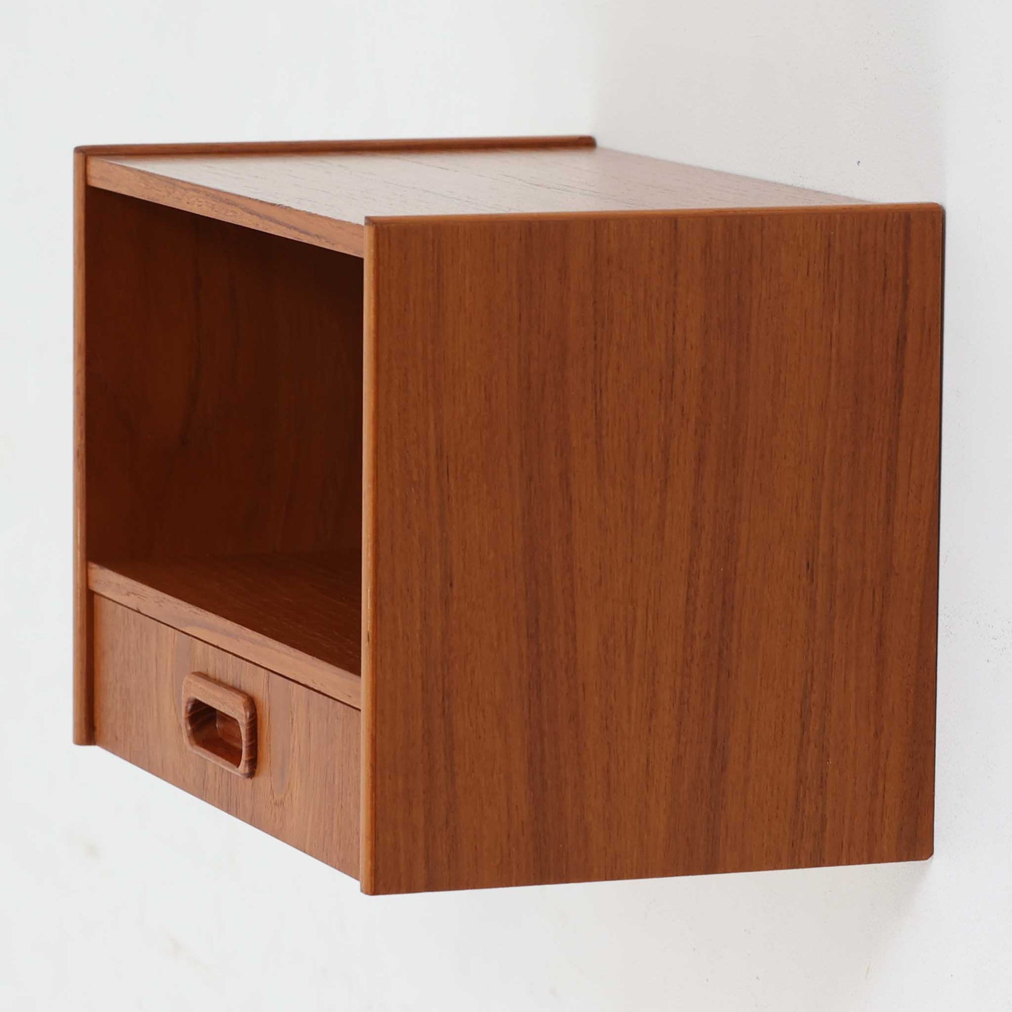 スウェーデン製チーク材ウォールシェルフです。壁面にすっきりと収まるコンパクトなサイズに、オープン棚と引き出しを組み合わせた実用性の高いデザインが魅力。丸みを帯びた側板や掘り込み式の引き手が北欧らしい柔らかな印象を添え、チーク材の美しい木目と経年で深みを増した艶が上質な存在感を演出します。お気に入りのオブジェや本、時計を飾るディスプレイスペースとしてはもちろん、玄関やベッドサイドで小物収納としても活躍。限られた空間を有効活用しながら、ビンテージならではの温もりと希少性を楽しめる一台です。