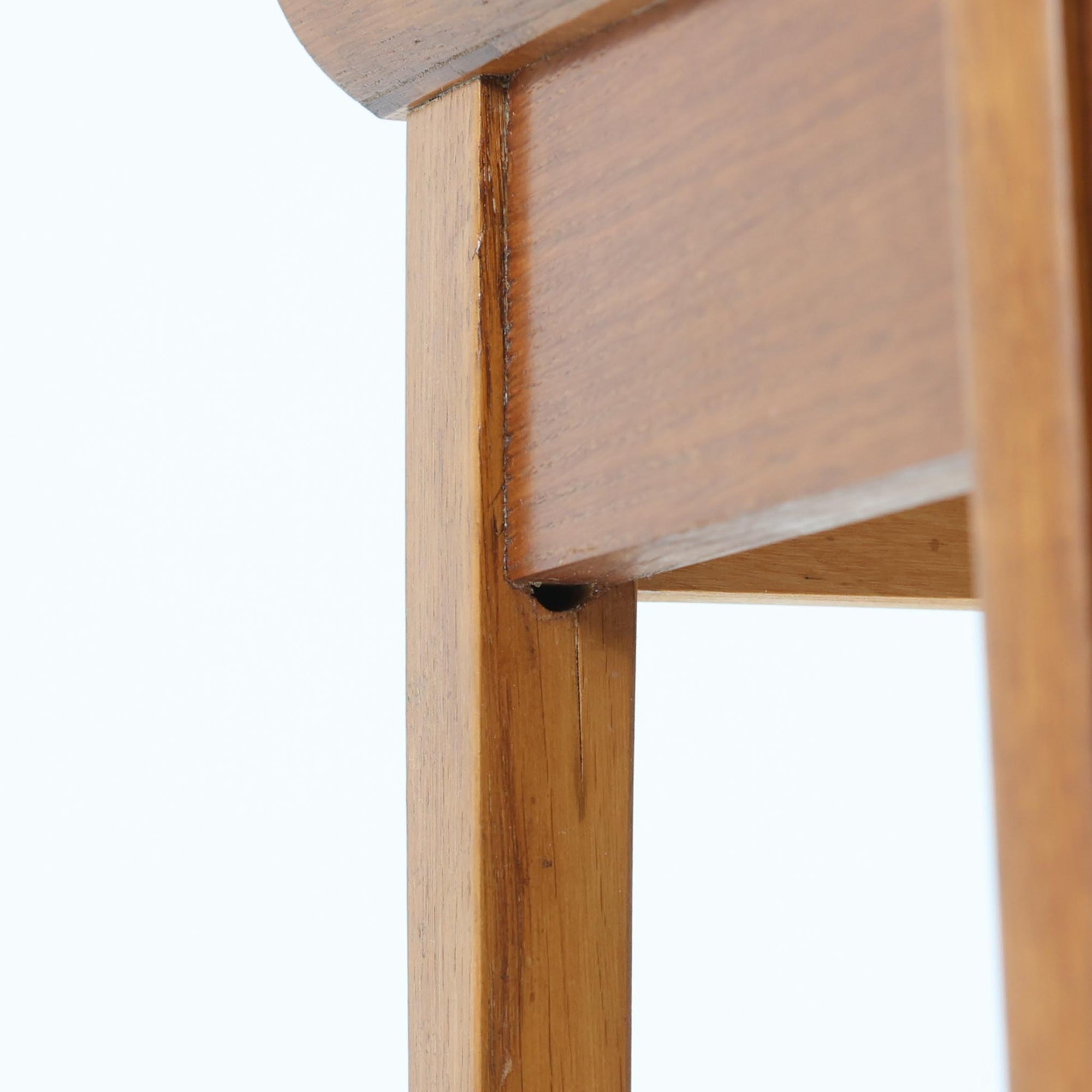 スウェーデンで製作されたコンソールテーブルです。天板にはチーク材、脚部にはオーク材を組み合わせ、温かみのある木目と落ち着いた色合いが北欧らしい上品な雰囲気を演出します。天板下には引き出しが備えられており、小物や文具などをすっきり収納できる実用的な構造。丸みを帯びた天板の角や細身のテーパー脚が軽やかな印象を与え、玄関やリビング、ベッドサイドなど限られたスペースにも収まりやすいサイズ感です。経年により深みを増した木部の表情が魅力の北欧ビンテージ家具です。