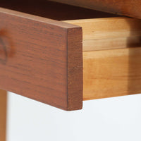 スウェーデンで製作されたコンソールテーブルです。天板にはチーク材、脚部にはオーク材を組み合わせ、温かみのある木目と落ち着いた色合いが北欧らしい上品な雰囲気を演出します。天板下には引き出しが備えられており、小物や文具などをすっきり収納できる実用的な構造。丸みを帯びた天板の角や細身のテーパー脚が軽やかな印象を与え、玄関やリビング、ベッドサイドなど限られたスペースにも収まりやすいサイズ感です。経年により深みを増した木部の表情が魅力の北欧ビンテージ家具です。