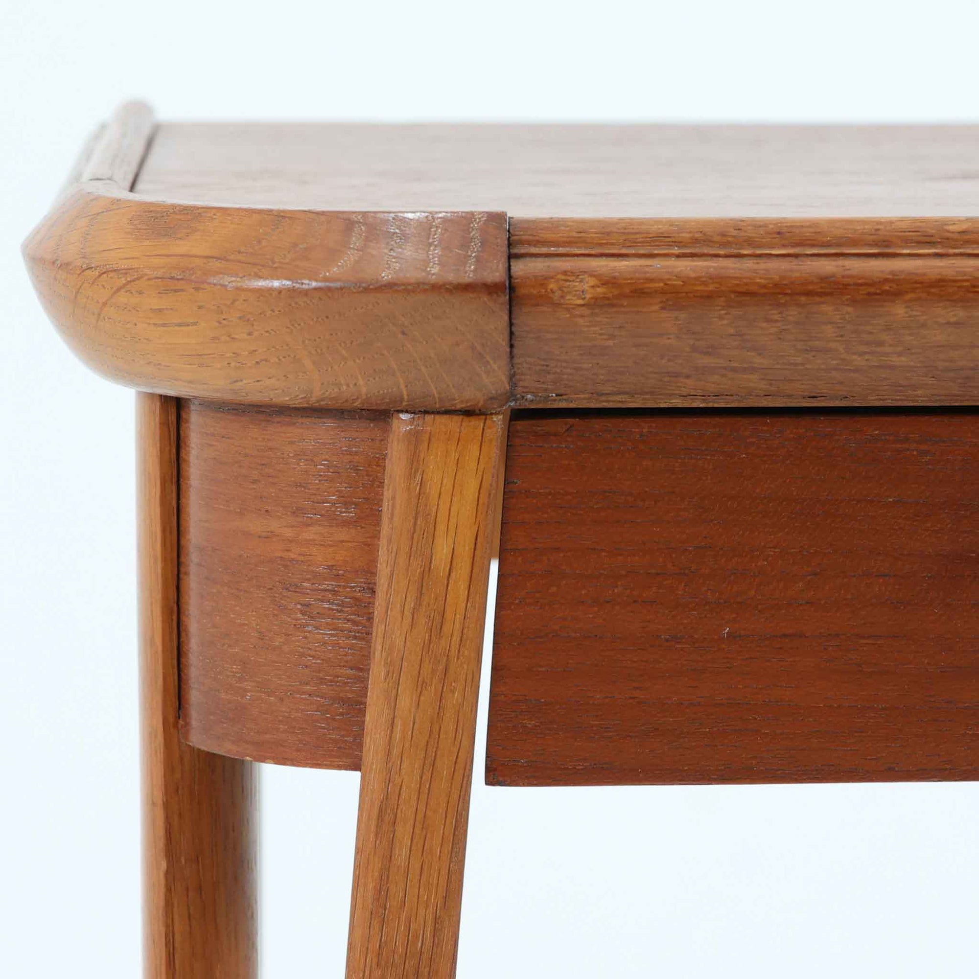 スウェーデンで製作されたコンソールテーブルです。天板にはチーク材、脚部にはオーク材を組み合わせ、温かみのある木目と落ち着いた色合いが北欧らしい上品な雰囲気を演出します。天板下には引き出しが備えられており、小物や文具などをすっきり収納できる実用的な構造。丸みを帯びた天板の角や細身のテーパー脚が軽やかな印象を与え、玄関やリビング、ベッドサイドなど限られたスペースにも収まりやすいサイズ感です。経年により深みを増した木部の表情が魅力の北欧ビンテージ家具です。