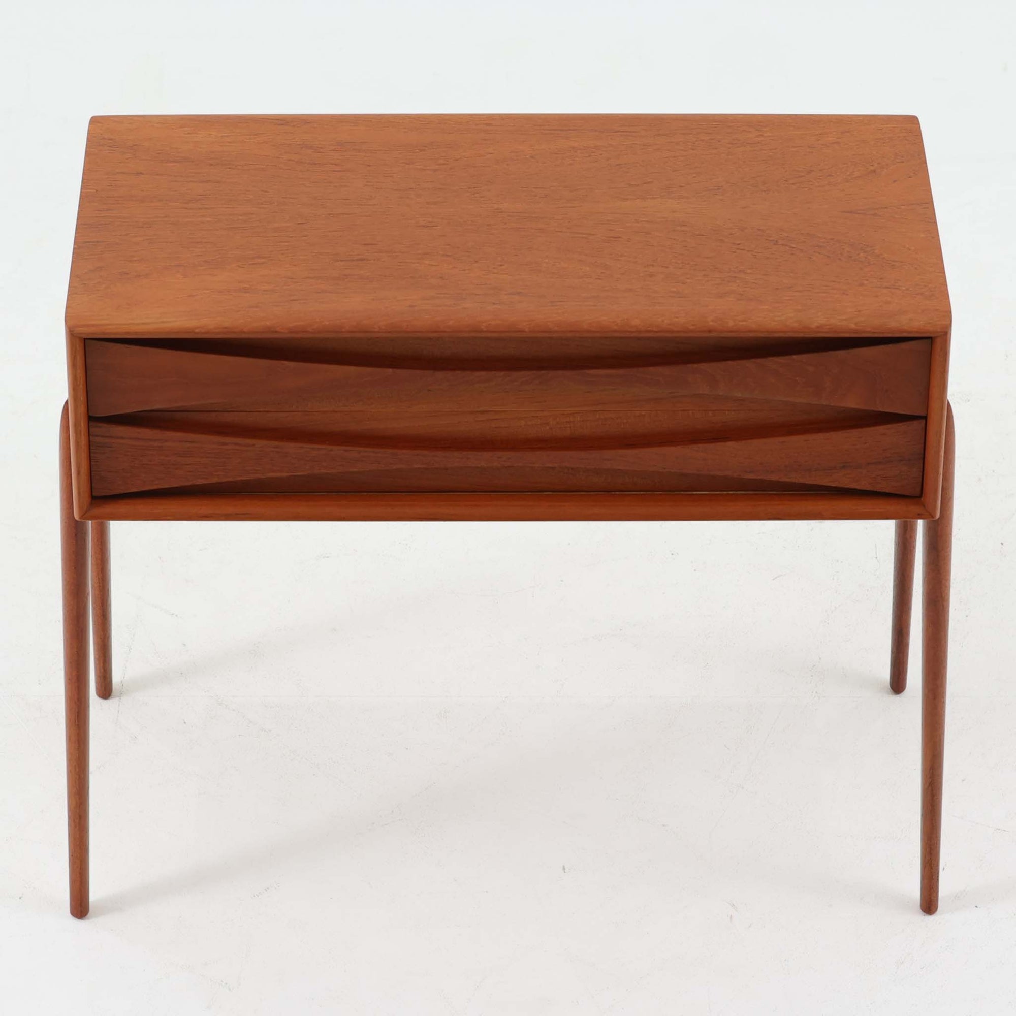 Rimbert Sandholdtがデザインし、Ateljé Glas &amp; Träが手掛けたModel 6835の2段チェストです。チーク材の美しい木目と経年により深みを増した色艶に加え、引き出し前板に施された立体的な波状の削り出しデザインが印象的で、彫刻的な存在感を放ちます。シンプルな構造の中に高い造形美が感じられ、細身の脚部が軽やかな印象を添えます。コンパクトなサイズ感でベッドサイドやリビングでの小物収納に適し、空間のアクセントとしても映える希少性の高いビンテージアイテムです。