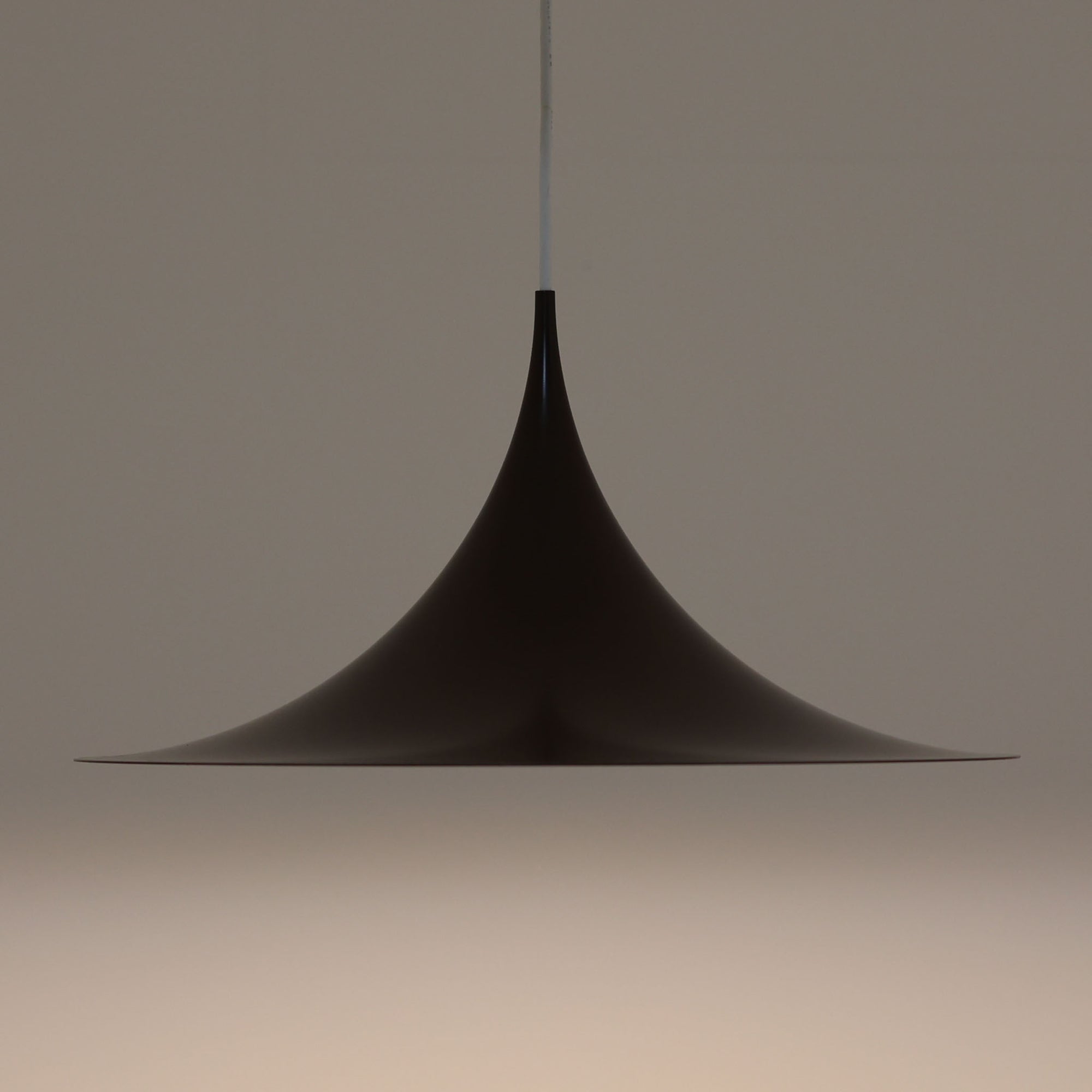 Claus BonderupとTorsten Thorupによるデザインのペンダントライト「Semi」は、Fog & Morup社から発表された北欧モダンを象徴する名作です。直径47cmのアルミシェードは美しい円錐を上下で切り取ったような独特のフォルムを持ち、光を下方向へ効率的に導きます。そのシャープでミニマルな造形は、空間にモダンな緊張感と優雅さをもたらし、ダイニングやリビングの中心を引き立てます。ビンテージならではの希少性と時を経た質感が一層の魅力を添え、北欧デザインの洗練を感じさせる一灯です。