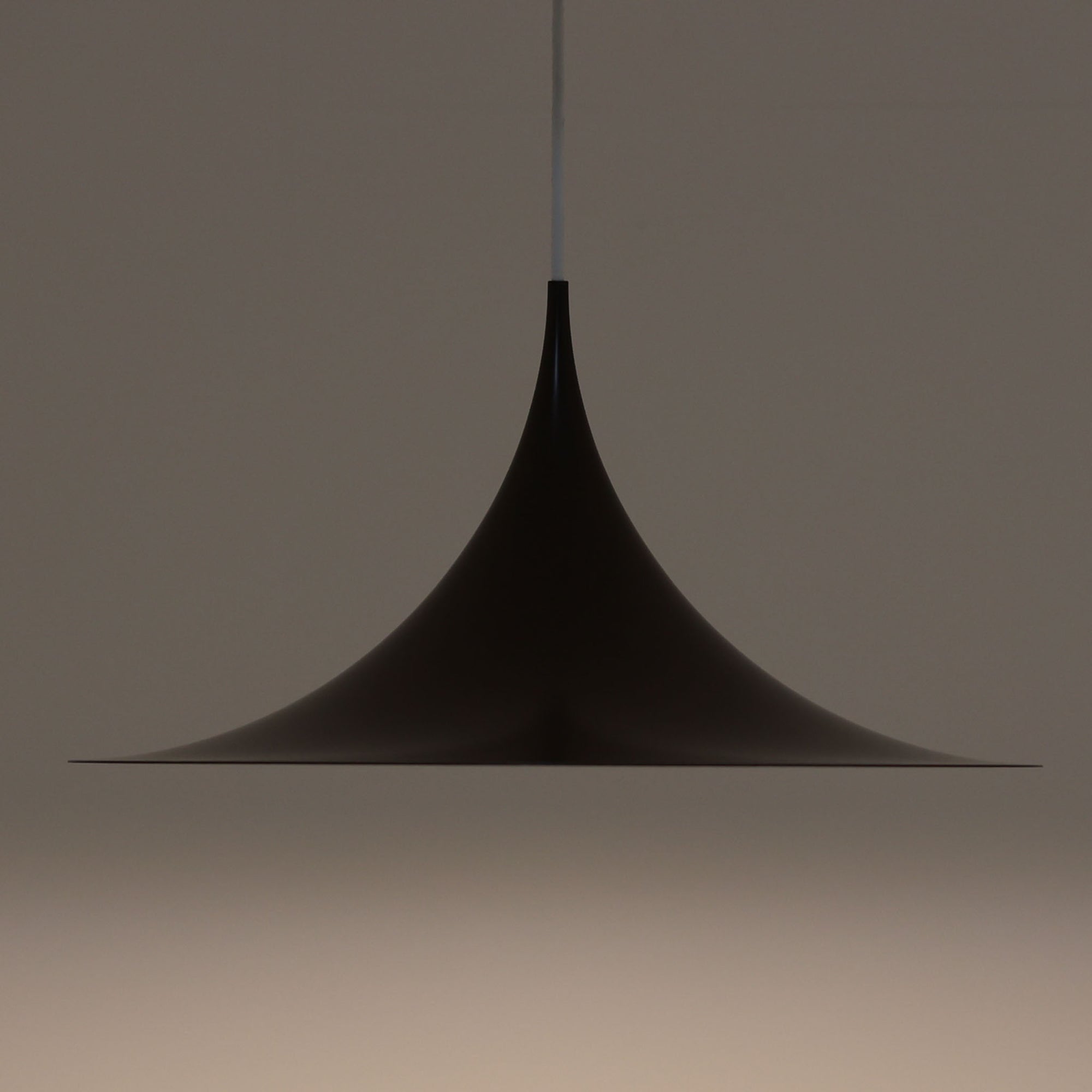 Claus BonderupとTorsten Thorupによるデザインのペンダントライト「Semi」は、Fog & Morup社から発表された北欧モダンを象徴する名作です。直径47cmのアルミシェードは美しい円錐を上下で切り取ったような独特のフォルムを持ち、光を下方向へ効率的に導きます。そのシャープでミニマルな造形は、空間にモダンな緊張感と優雅さをもたらし、ダイニングやリビングの中心を引き立てます。ビンテージならではの希少性と時を経た質感が一層の魅力を添え、北欧デザインの洗練を感じさせる一灯です。