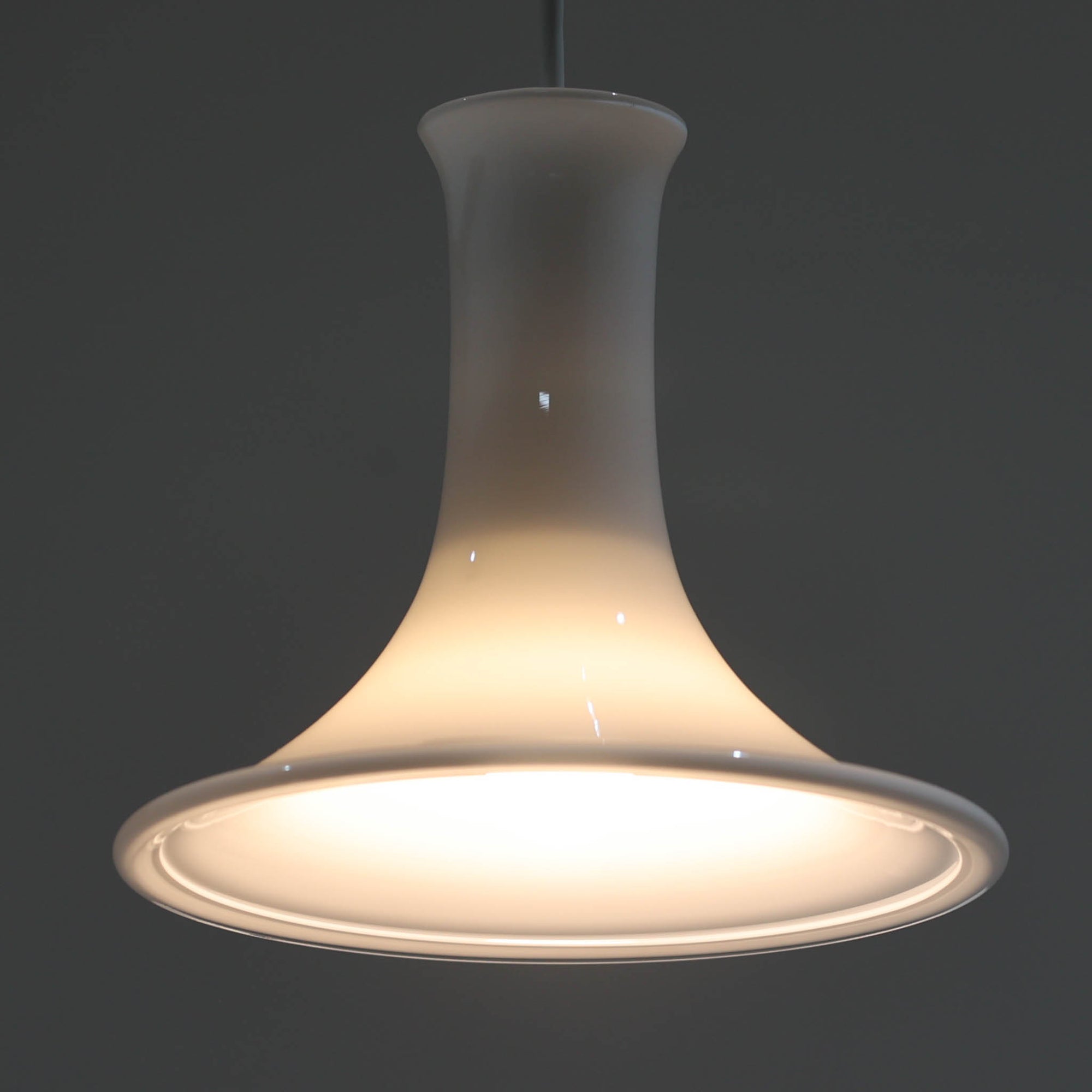 Michael BangがデザインしたMandarinペンダントライトです。Holmegaardならではの高品質なガラスを用いた美しいフォルムが特徴で、滑らかに広がるシェードと細く立ち上がるネック部分が軽やかで洗練された印象を与えます。乳白色ガラスを通して放たれる柔らかな光は空間全体を穏やかに包み込み、ダイニングやカウンター、寝室など幅広いシーンで活躍します。扱いやすいサイズ感と、北欧デザイン黄金期を感じさせる造形美が魅力の希少なビンテージ照明です。