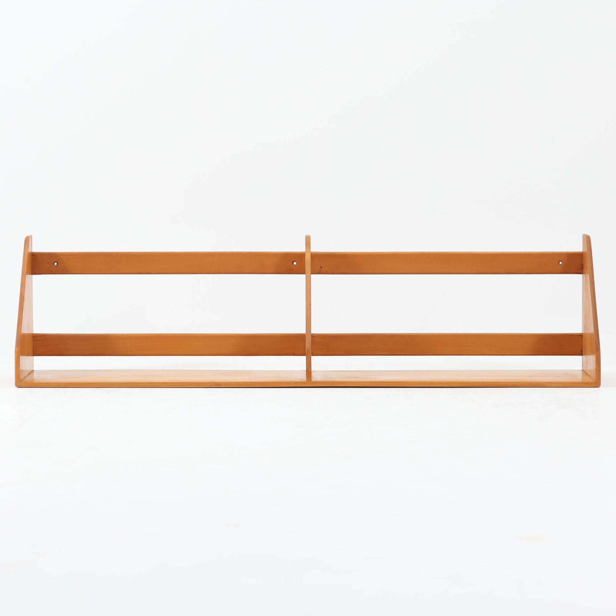 Borge Mogensen（ボーエ・モーエンセン）デザイン、FDB Mobler製のウォールシェルフ Model B5です。ビーチ無垢材を使用したシンプルで温かみのあるデザインが特徴で、北欧家具ならではの機能性と美しさを兼ね備えています。両サイドのパネルと背面のバー構造により、収納物が安定しやすく、実用性の高い設計となっています。中央の仕切りによって本や小物を整理しやすく、キッチンやリビング、書斎などさまざまな空間で活躍します。素朴で飽きのこないフォルムは、モーエンセンの「日常生活のための家具」という思想を体現したデザイン。デンマーク製の北欧ビンテージならではの味わい深い木の質感が魅力の一品です。