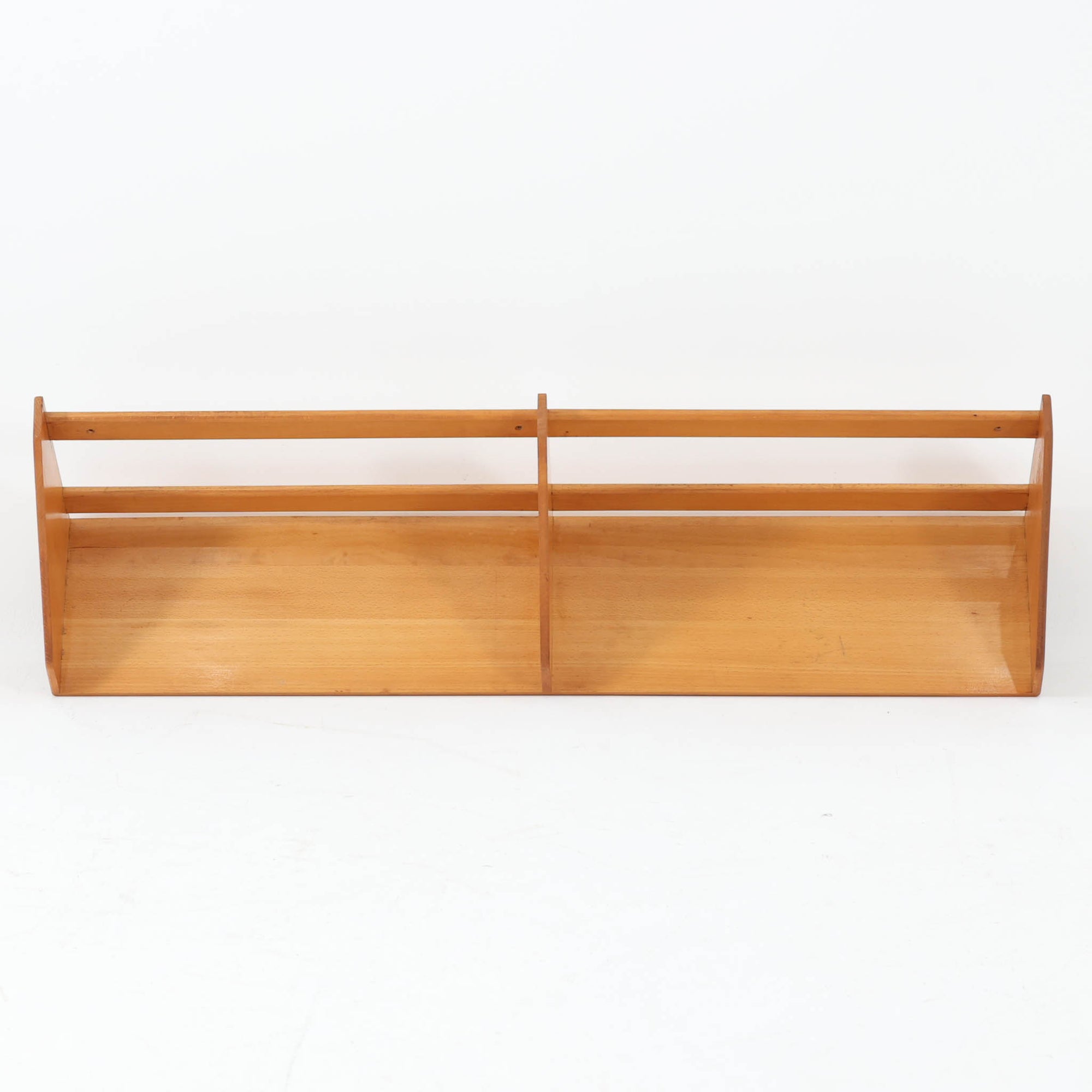 Borge Mogensen（ボーエ・モーエンセン）デザイン、FDB Mobler製のウォールシェルフ Model B5です。ビーチ無垢材を使用したシンプルで温かみのあるデザインが特徴で、北欧家具ならではの機能性と美しさを兼ね備えています。両サイドのパネルと背面のバー構造により、収納物が安定しやすく、実用性の高い設計となっています。中央の仕切りによって本や小物を整理しやすく、キッチンやリビング、書斎などさまざまな空間で活躍します。素朴で飽きのこないフォルムは、モーエンセンの「日常生活のための家具」という思想を体現したデザイン。デンマーク製の北欧ビンテージならではの味わい深い木の質感が魅力の一品です。