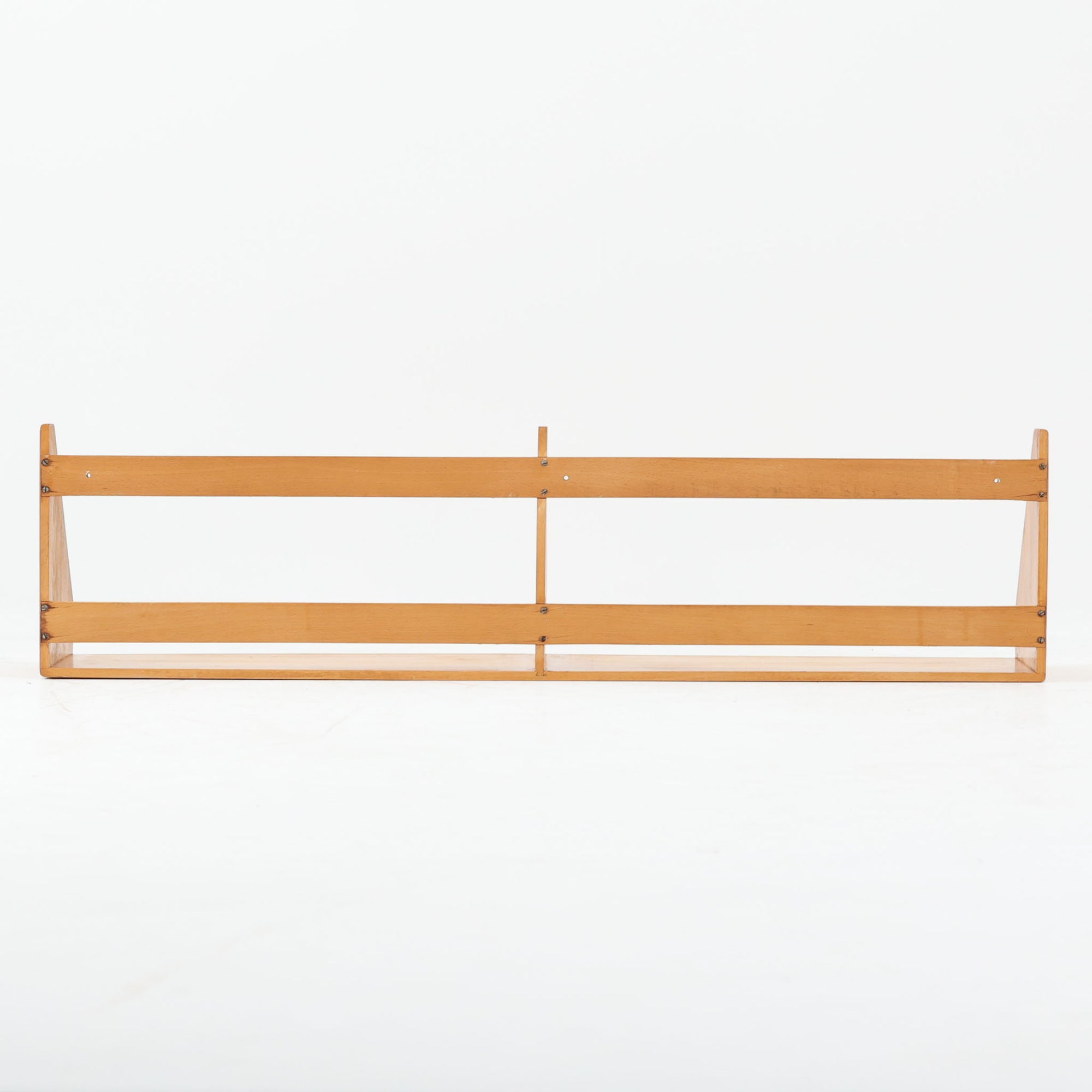 Borge Mogensen（ボーエ・モーエンセン）デザイン、FDB Mobler製のウォールシェルフ Model B5です。ビーチ無垢材を使用したシンプルで温かみのあるデザインが特徴で、北欧家具ならではの機能性と美しさを兼ね備えています。両サイドのパネルと背面のバー構造により、収納物が安定しやすく、実用性の高い設計となっています。中央の仕切りによって本や小物を整理しやすく、キッチンやリビング、書斎などさまざまな空間で活躍します。素朴で飽きのこないフォルムは、モーエンセンの「日常生活のための家具」という思想を体現したデザイン。デンマーク製の北欧ビンテージならではの味わい深い木の質感が魅力の一品です。