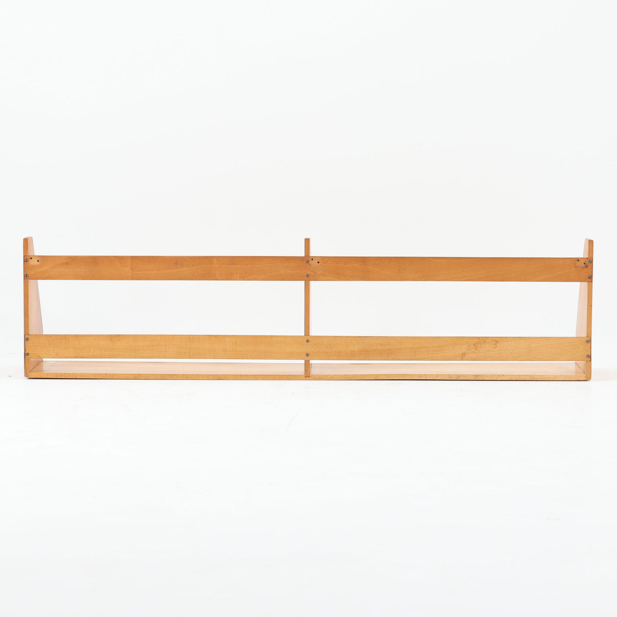 Borge Mogensen（ボーエ・モーエンセン）デザイン、FDB Mobler製のウォールシェルフ Model B5です。ビーチ無垢材を使用したシンプルで温かみのあるデザインが特徴で、北欧家具ならではの機能性と美しさを兼ね備えています。両サイドのパネルと背面のバー構造により、収納物が安定しやすく、実用性の高い設計となっています。中央の仕切りによって本や小物を整理しやすく、キッチンやリビング、書斎などさまざまな空間で活躍します。素朴で飽きのこないフォルムは、モーエンセンの「日常生活のための家具」という思想を体現したデザイン。デンマーク製の北欧ビンテージならではの味わい深い木の質感が魅力の一品です。