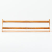 Borge Mogensen（ボーエ・モーエンセン）デザイン、FDB Mobler製のウォールシェルフ Model B5です。ビーチ無垢材を使用したシンプルで温かみのあるデザインが特徴で、北欧家具ならではの機能性と美しさを兼ね備えています。両サイドのパネルと背面のバー構造により、収納物が安定しやすく、実用性の高い設計となっています。中央の仕切りによって本や小物を整理しやすく、キッチンやリビング、書斎などさまざまな空間で活躍します。素朴で飽きのこないフォルムは、モーエンセンの「日常生活のための家具」という思想を体現したデザイン。デンマーク製の北欧ビンテージならではの味わい深い木の質感が魅力の一品です。