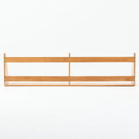 Borge Mogensen（ボーエ・モーエンセン）デザイン、FDB Mobler製のウォールシェルフ Model B5です。ビーチ無垢材を使用したシンプルで温かみのあるデザインが特徴で、北欧家具ならではの機能性と美しさを兼ね備えています。両サイドのパネルと背面のバー構造により、収納物が安定しやすく、実用性の高い設計となっています。中央の仕切りによって本や小物を整理しやすく、キッチンやリビング、書斎などさまざまな空間で活躍します。素朴で飽きのこないフォルムは、モーエンセンの「日常生活のための家具」という思想を体現したデザイン。デンマーク製の北欧ビンテージならではの味わい深い木の質感が魅力の一品です。