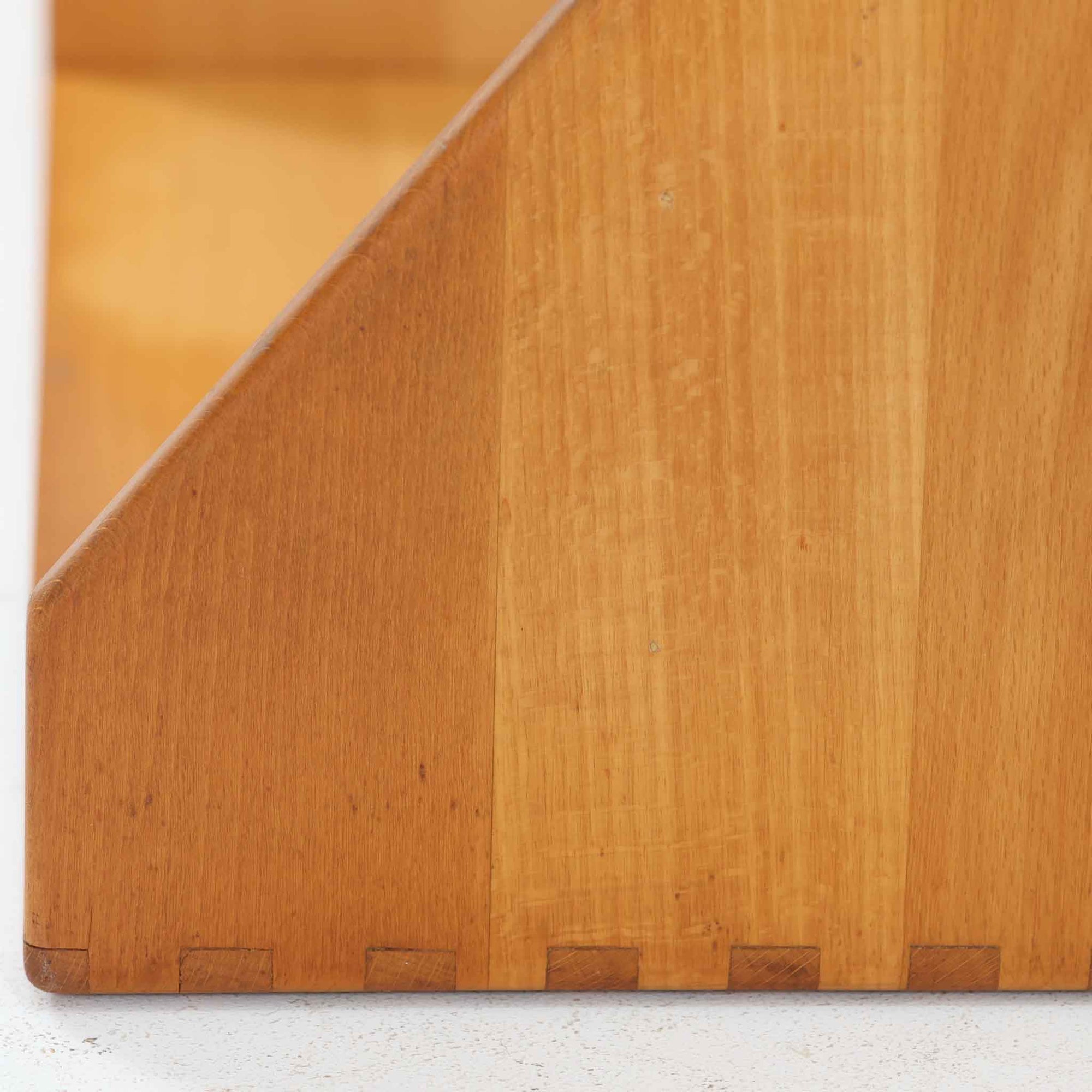 Borge Mogensen（ボーエ・モーエンセン）デザイン、FDB Mobler製のウォールシェルフ Model B5です。ビーチ無垢材を使用したシンプルで温かみのあるデザインが特徴で、北欧家具ならではの機能性と美しさを兼ね備えています。両サイドのパネルと背面のバー構造により、収納物が安定しやすく、実用性の高い設計となっています。中央の仕切りによって本や小物を整理しやすく、キッチンやリビング、書斎などさまざまな空間で活躍します。素朴で飽きのこないフォルムは、モーエンセンの「日常生活のための家具」という思想を体現したデザイン。デンマーク製の北欧ビンテージならではの味わい深い木の質感が魅力の一品です。