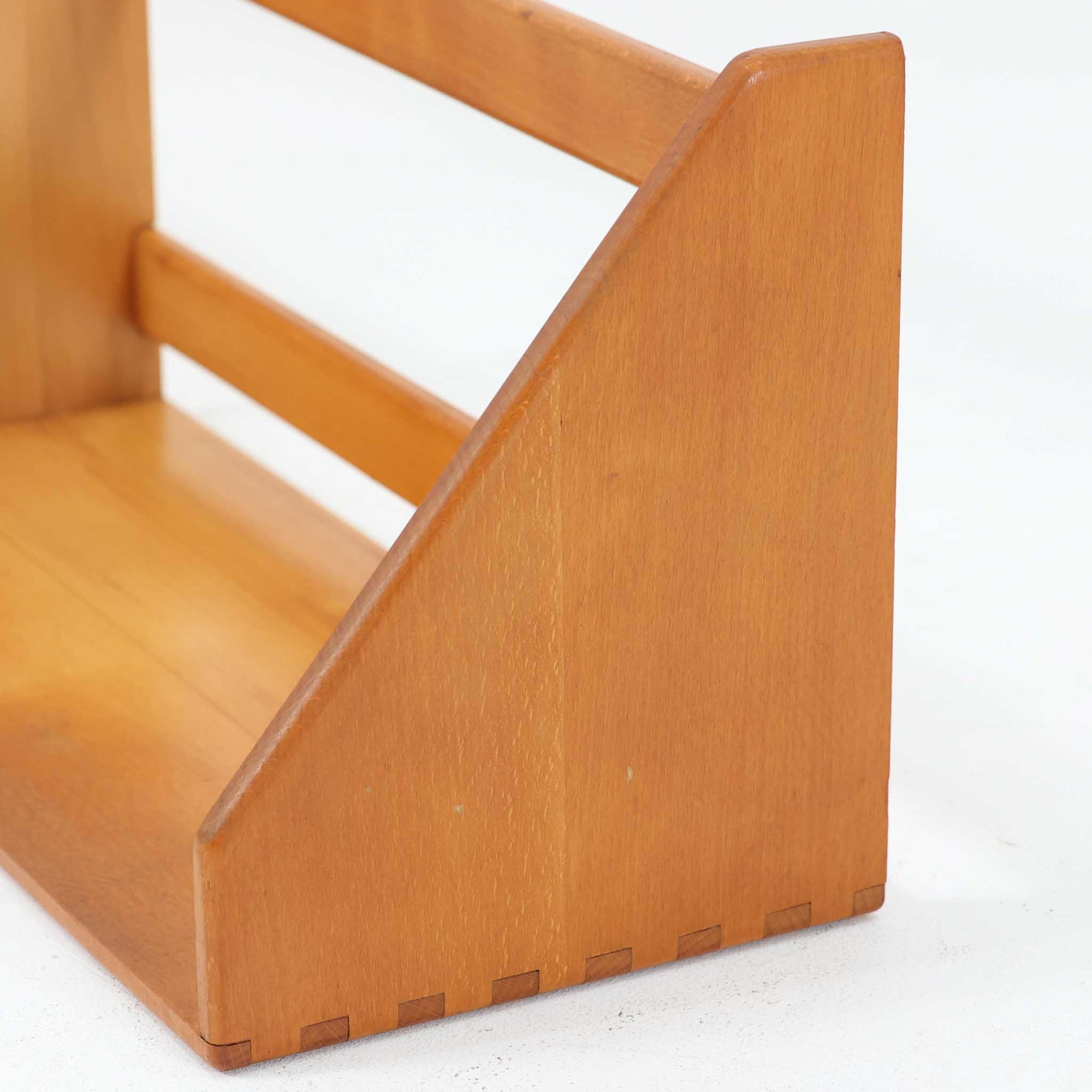 Borge Mogensen（ボーエ・モーエンセン）デザイン、FDB Mobler製のウォールシェルフ Model B5です。ビーチ無垢材を使用したシンプルで温かみのあるデザインが特徴で、北欧家具ならではの機能性と美しさを兼ね備えています。両サイドのパネルと背面のバー構造により、収納物が安定しやすく、実用性の高い設計となっています。中央の仕切りによって本や小物を整理しやすく、キッチンやリビング、書斎などさまざまな空間で活躍します。素朴で飽きのこないフォルムは、モーエンセンの「日常生活のための家具」という思想を体現したデザイン。デンマーク製の北欧ビンテージならではの味わい深い木の質感が魅力の一品です。