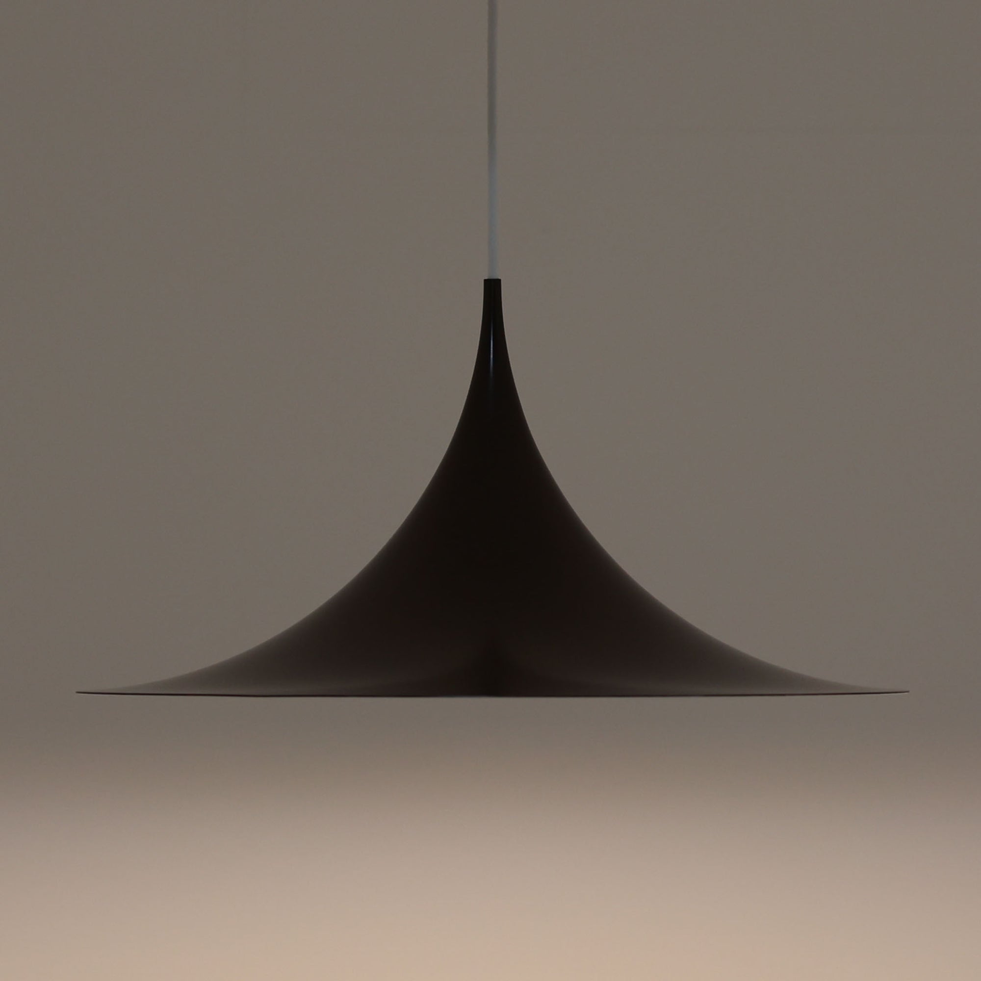 Claus BonderupとTorsten Thorupによるデザインのペンダントライト「Semi」は、Fog & Morup社から発表された北欧モダンを象徴する名作です。直径47cmのアルミシェードは美しい円錐を上下で切り取ったような独特のフォルムを持ち、光を下方向へ効率的に導きます。そのシャープでミニマルな造形は、空間にモダンな緊張感と優雅さをもたらし、ダイニングやリビングの中心を引き立てます。ビンテージならではの希少性と時を経た質感が一層の魅力を添え、北欧デザインの洗練を感じさせる一灯です。