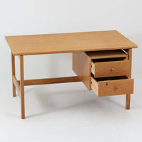 Hans J. Wegner（ハンス・J・ウェグナー）デザイン、Getama（ゲタマ）製GE156のオーク材片袖デスクです。幅125cmのゆとりある天板に、右側へ浮かぶように設けられた2段の片袖収納を組み合わせた、ウェグナーらしい端正な構造美が際立つ一台。無垢感のあるオークの木肌と軽快なフレーム構成が空間に明るく上質な印象をもたらし、書斎やホームオフィスはもちろん、ショップのワークテーブルとしても美しく映えます。引き出しは書類や文具を整理しやすく、下段には鍵付きで実用性も良好。名作椅子とも調和する洗練された佇まいと、北欧ビンテージならではの希少性が魅力のデスクです。