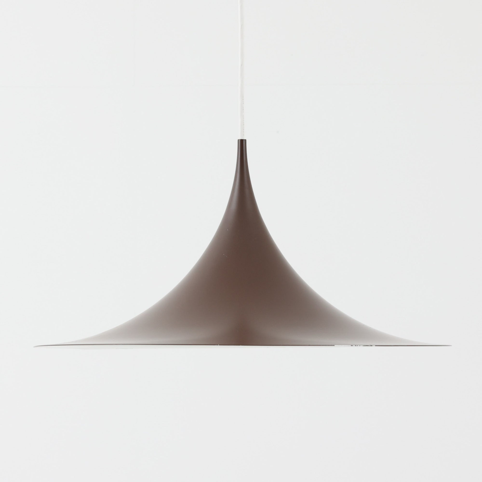 Claus BonderupとTorsten Thorupによるデザインのペンダントライト「Semi」は、Fog & Morup社から発表された北欧モダンを象徴する名作です。直径47cmのアルミシェードは美しい円錐を上下で切り取ったような独特のフォルムを持ち、光を下方向へ効率的に導きます。そのシャープでミニマルな造形は、空間にモダンな緊張感と優雅さをもたらし、ダイニングやリビングの中心を引き立てます。ビンテージならではの希少性と時を経た質感が一層の魅力を添え、北欧デザインの洗練を感じさせる一灯です。